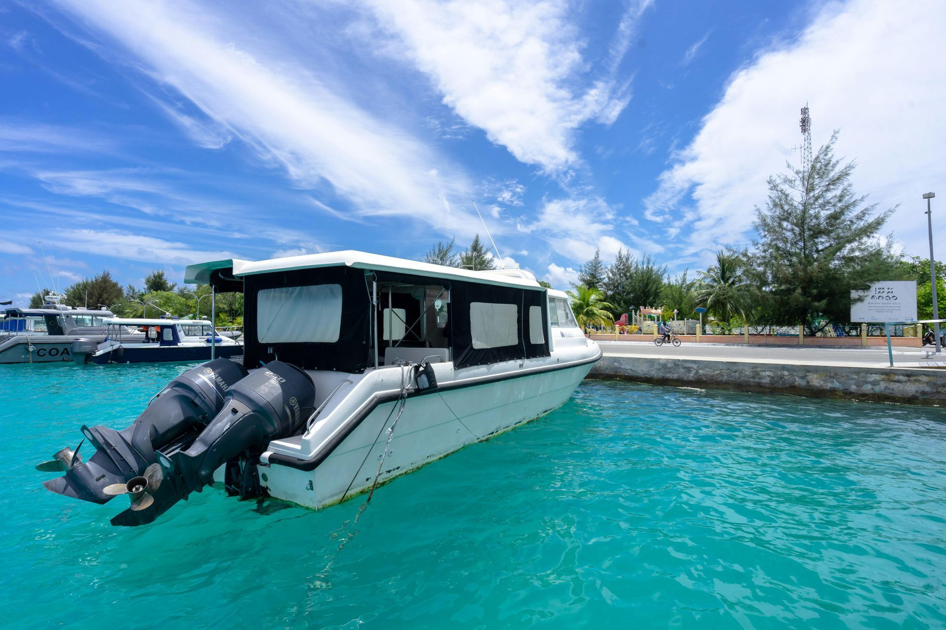A white boat is docked at a dock in the ocean.