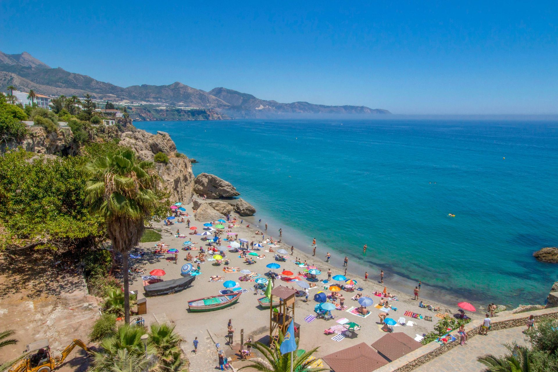 A beach filled with people and umbrellas on a sunny day in Costa Del Sol