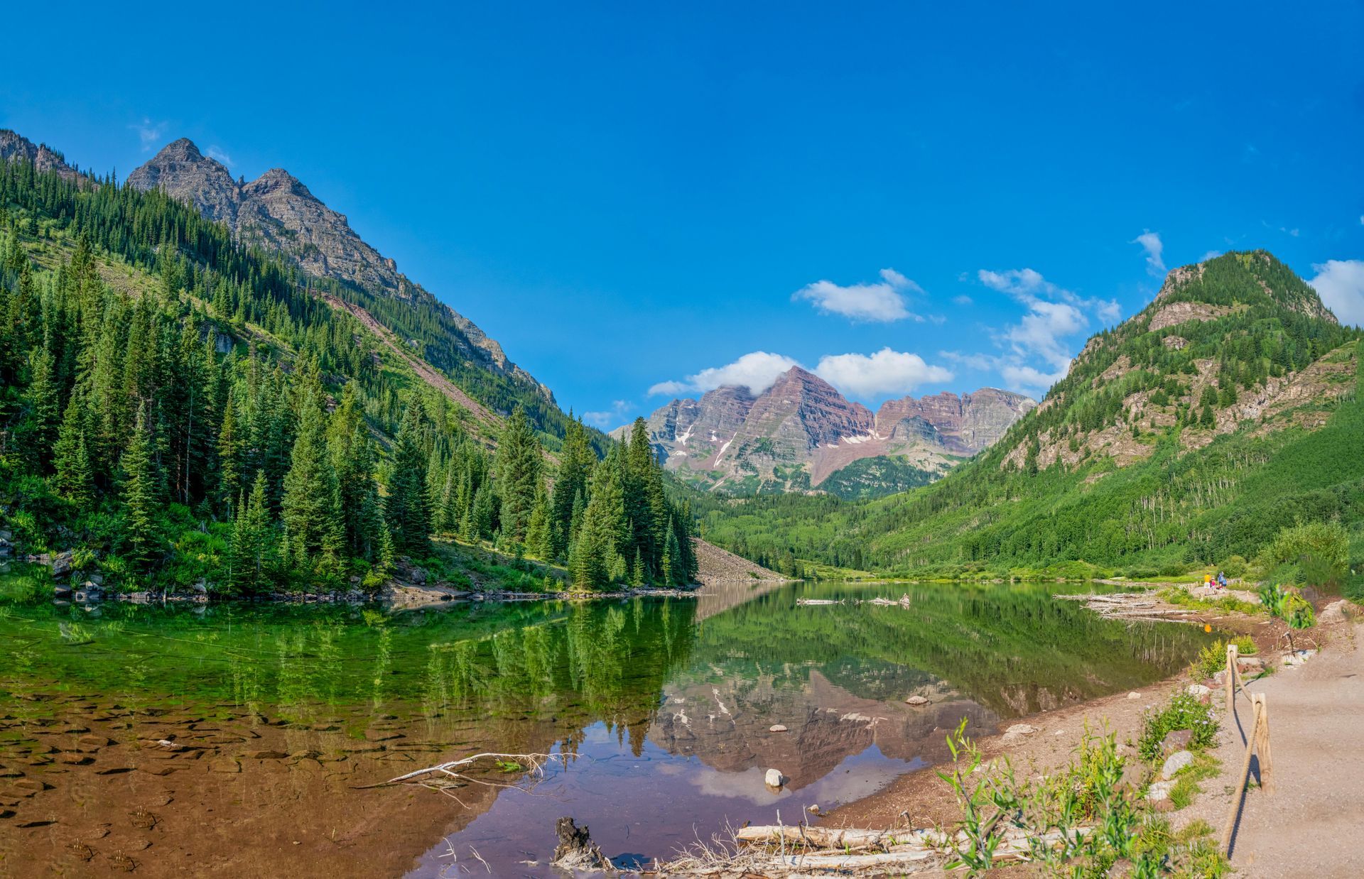 A lake surrounded by mountains and trees on a sunny day.