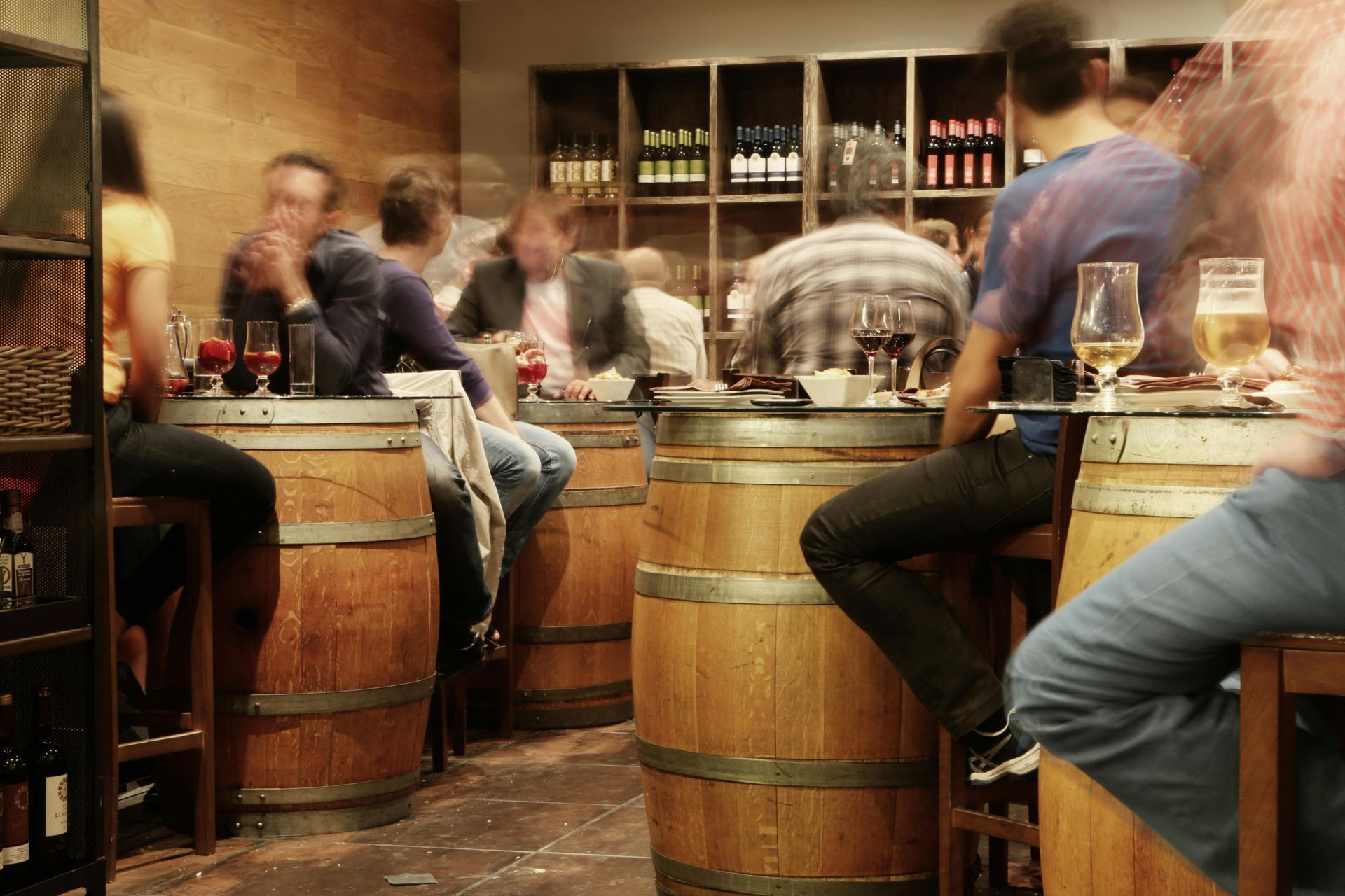 A group of people are sitting at wooden barrels in a bar.
