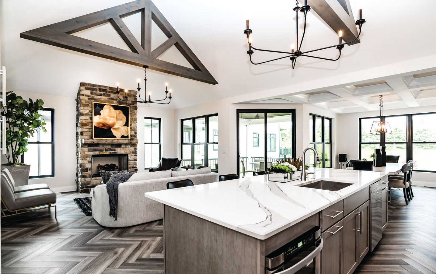 A stack of books sits on a wooden table, next to a lit candle and a warm cup of coffee or tea.