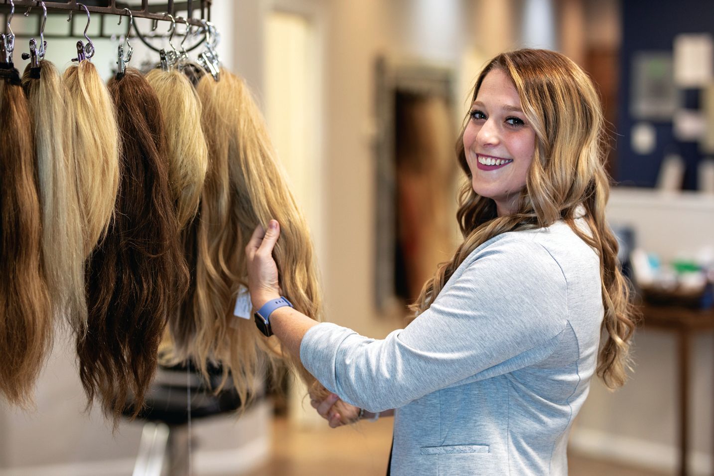 A stack of books sits on a wooden table, next to a lit candle and a warm cup of coffee or tea.