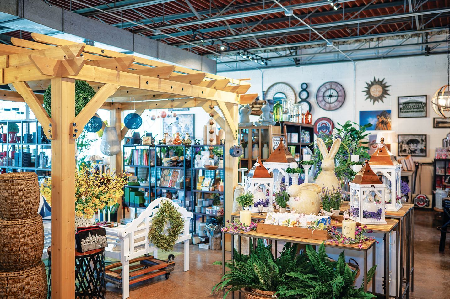 A stack of books sits on a wooden table, next to a lit candle and a warm cup of coffee or tea.