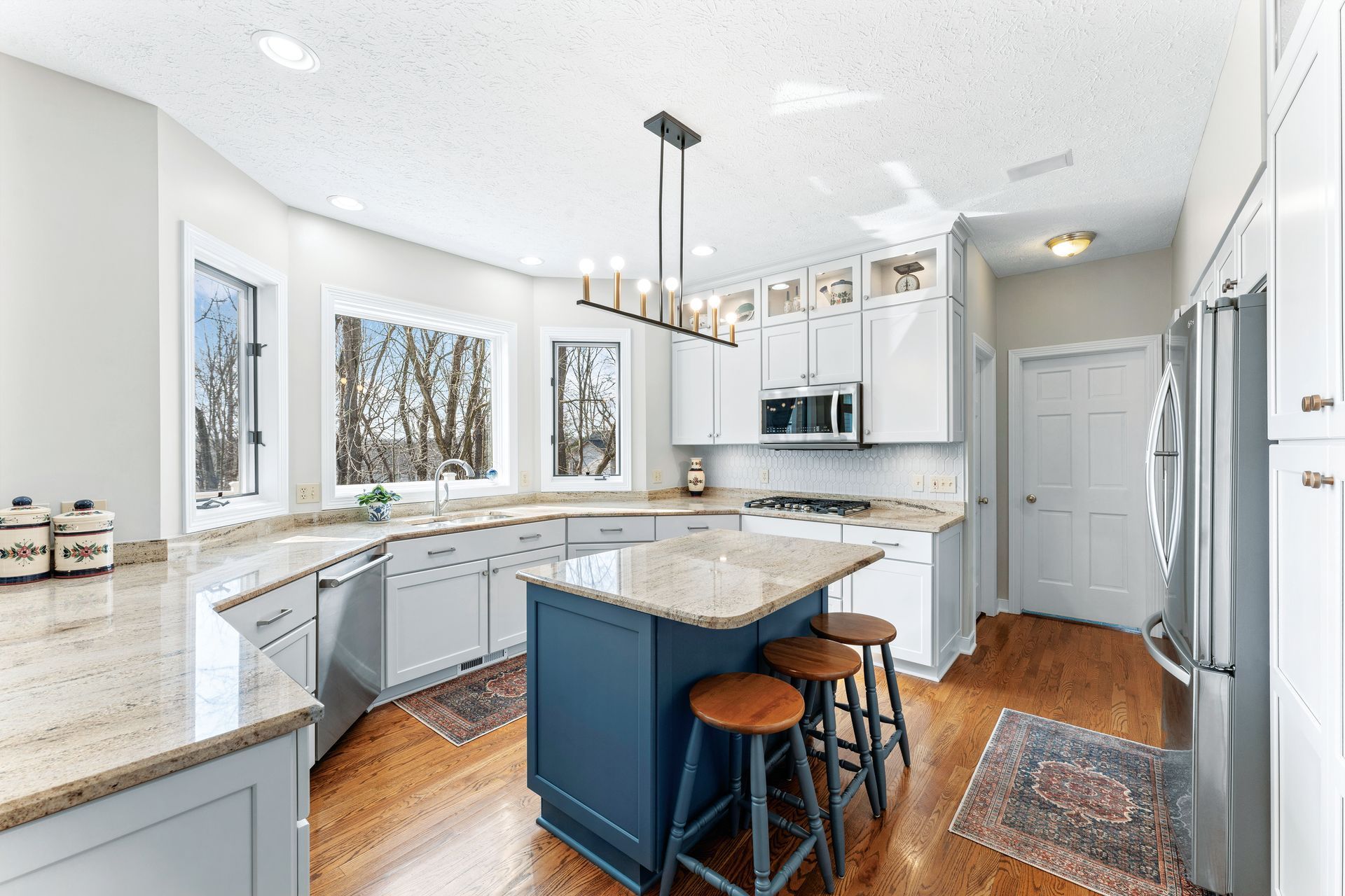 A stack of books sits on a wooden table, next to a lit candle and a warm cup of coffee or tea.