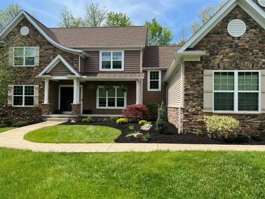 A stack of books sits on a wooden table, next to a lit candle and a warm cup of coffee or tea.