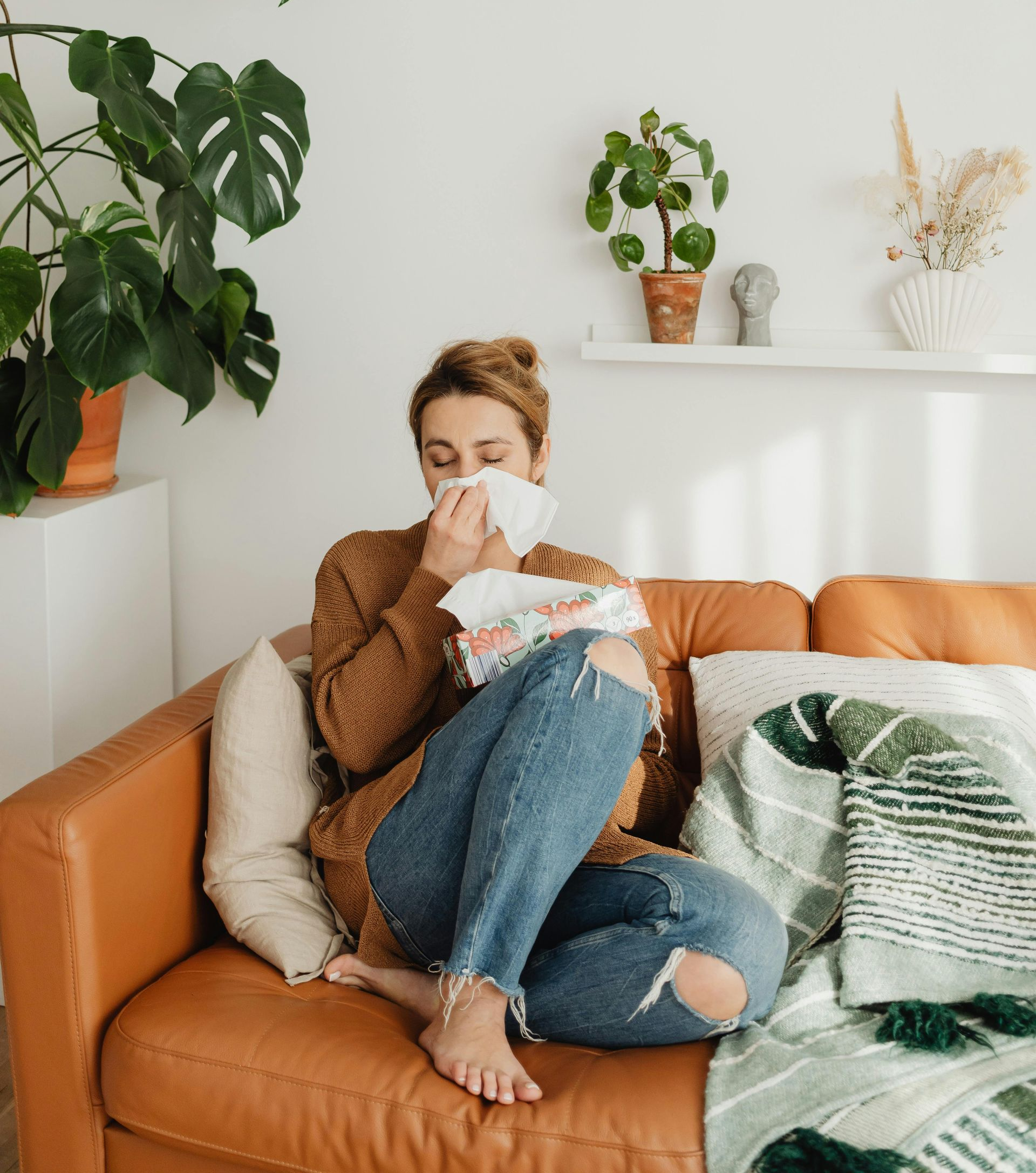 A pair of hands holds a white, open-top container filled with vibrant orange and purple flower buds.