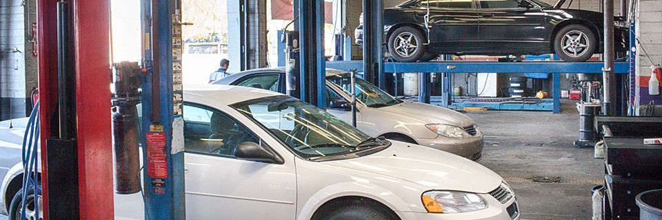A white car is sitting on a lift in a garage. | 19th Avenue Garage