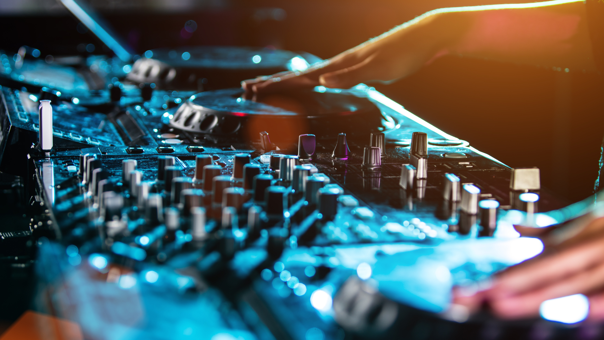 Close-up of a DJ's hands adjusting the controls on a professional DJ equipment setup, with colorful 