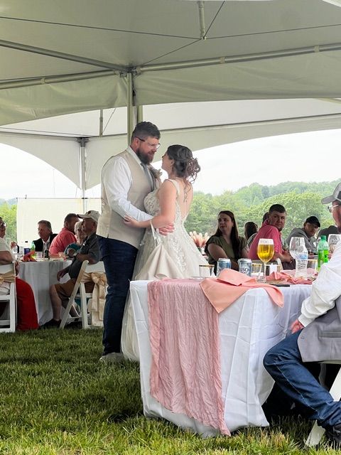K & D Disc Jockey & Karaoke providing DJ services at a private event. Bride and groom sharing a dance at their wedding reception under a tent, with guests enjoying the celebration in the background.