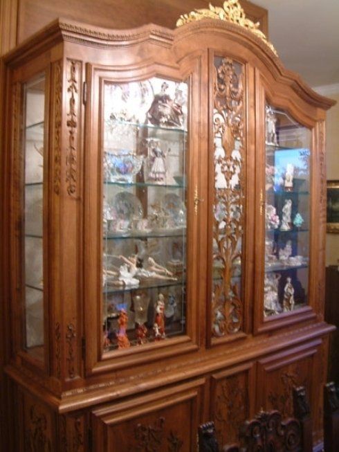 a large wooden cabinet with glass doors filled with plates and figurines