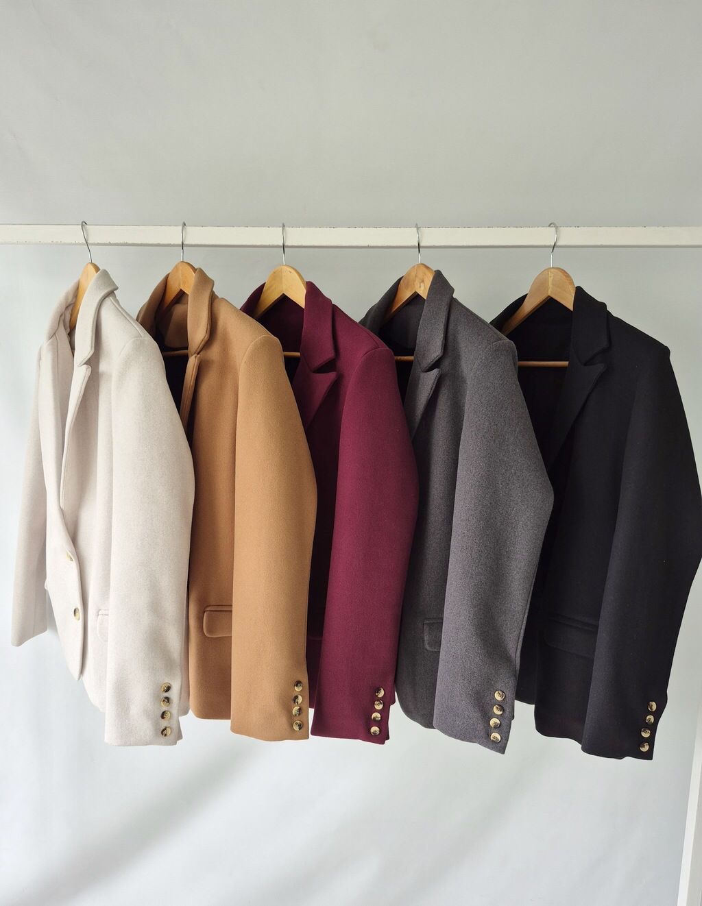Una fila de chaquetas colgadas en un perchero en diferentes colores.