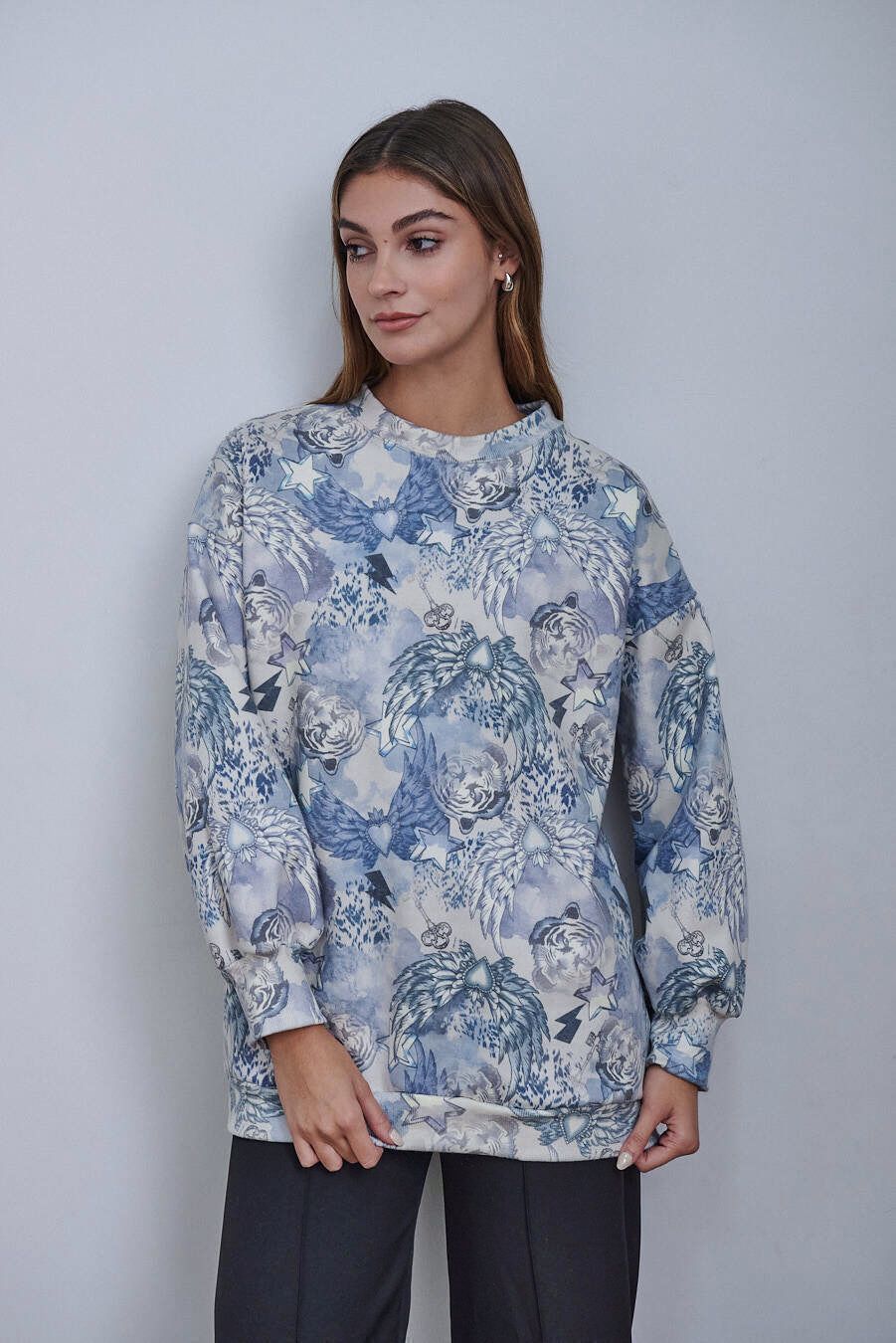 Una mujer lleva una sudadera azul y blanca y pantalones negros.