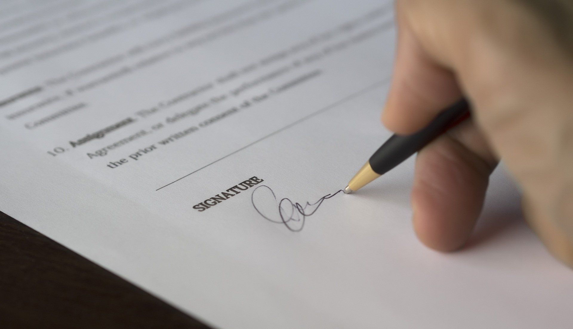 A person is signing a document with a pen.