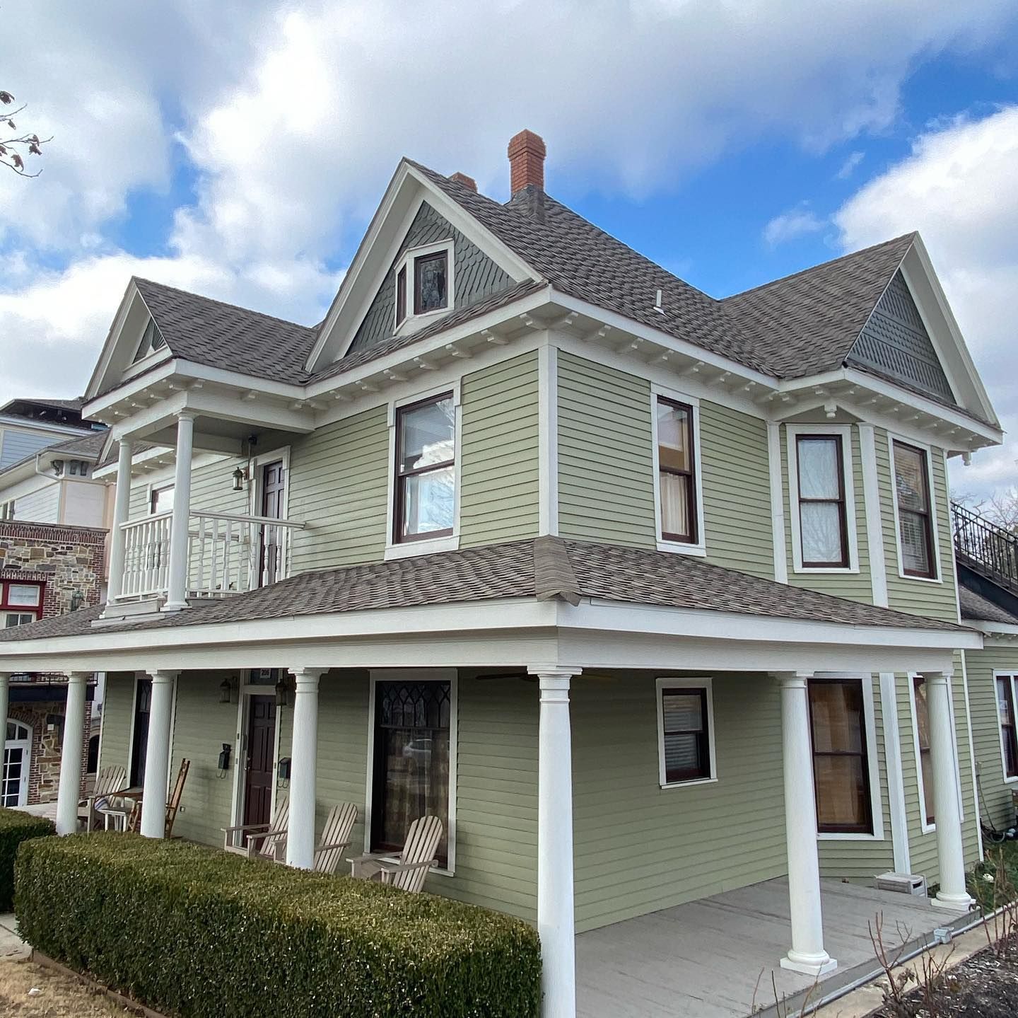 a green house with a porch and chairs on it