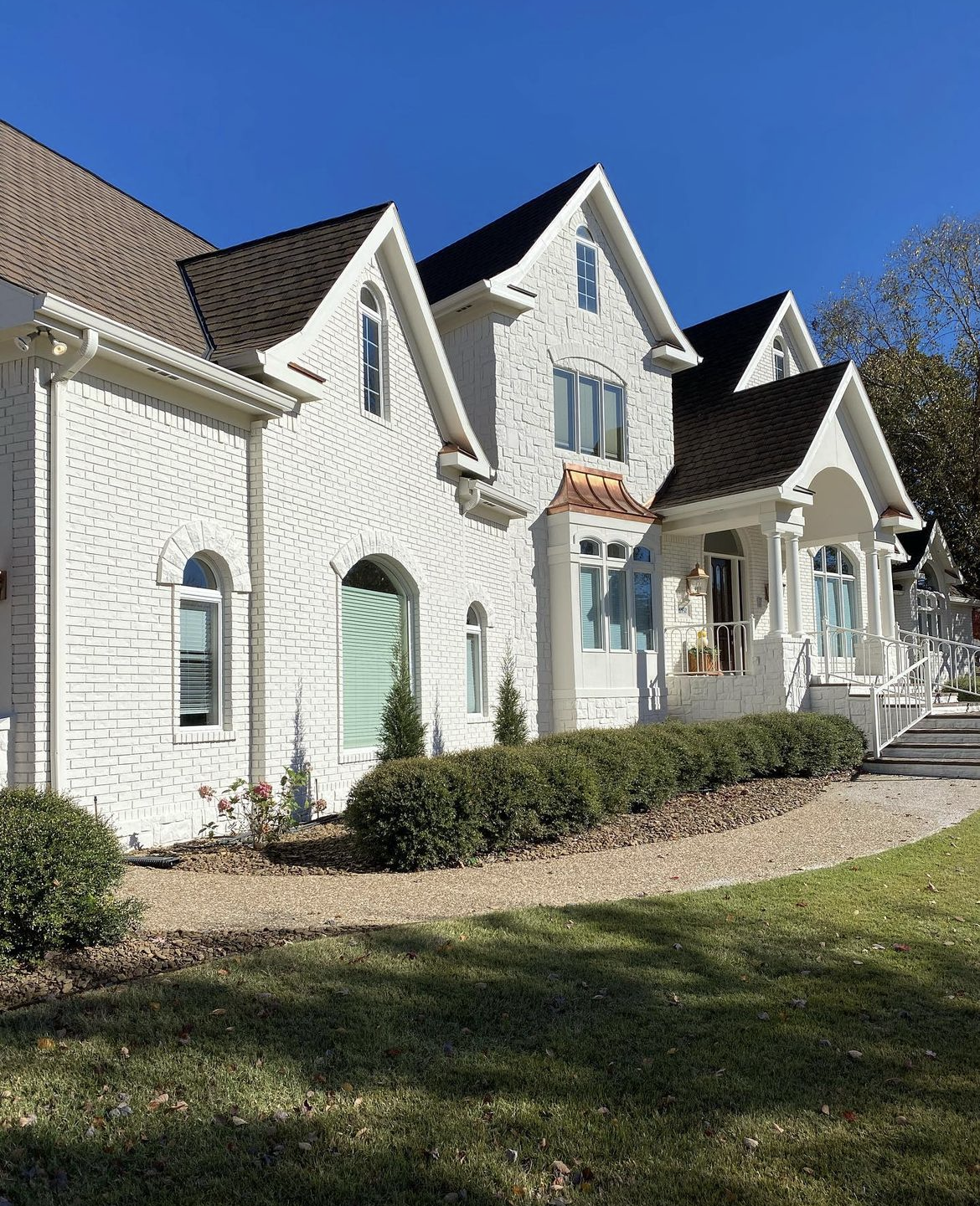 a large white house with a black roof is sitting on top of a lush green field .