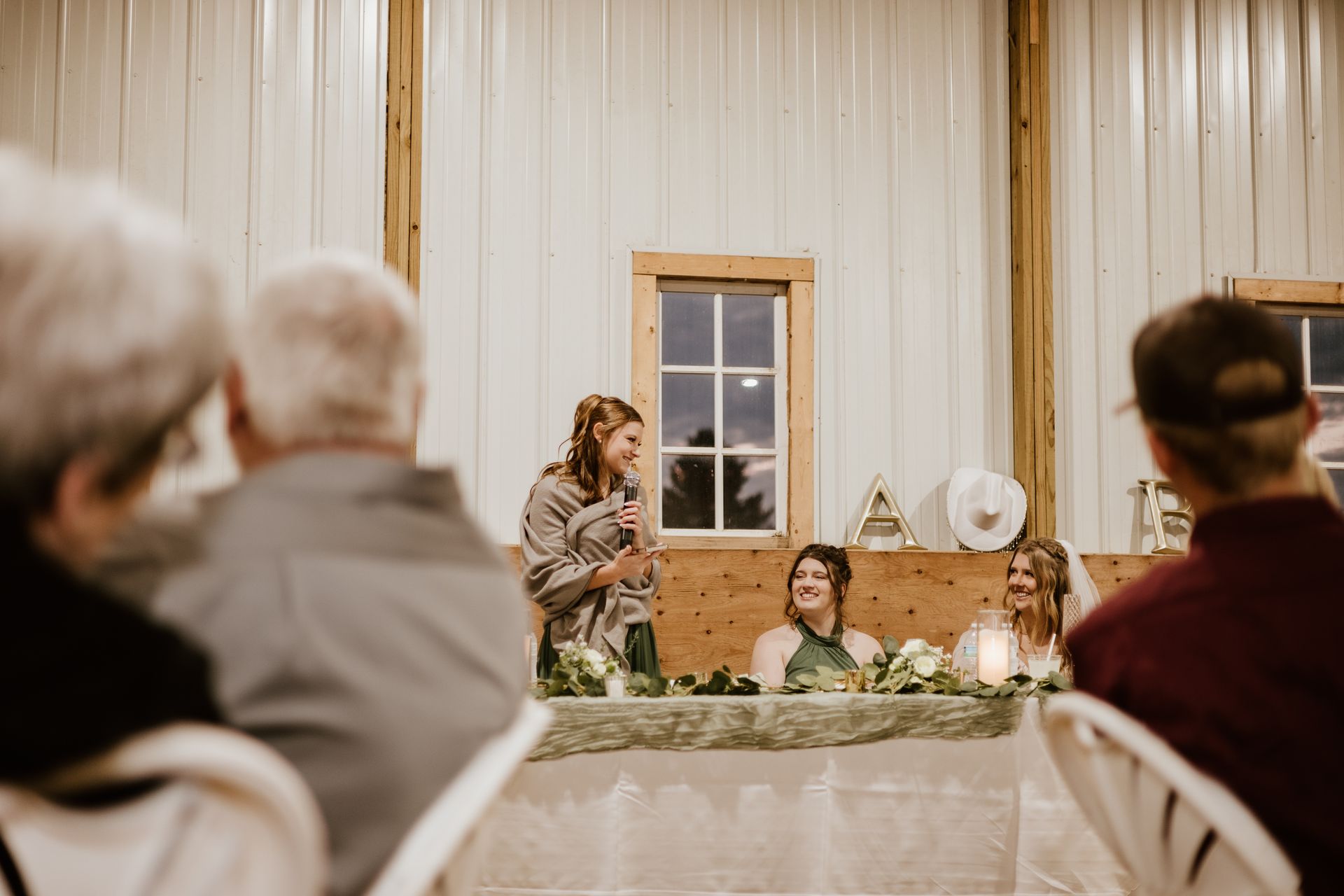 A woman is giving a speech at a wedding reception.