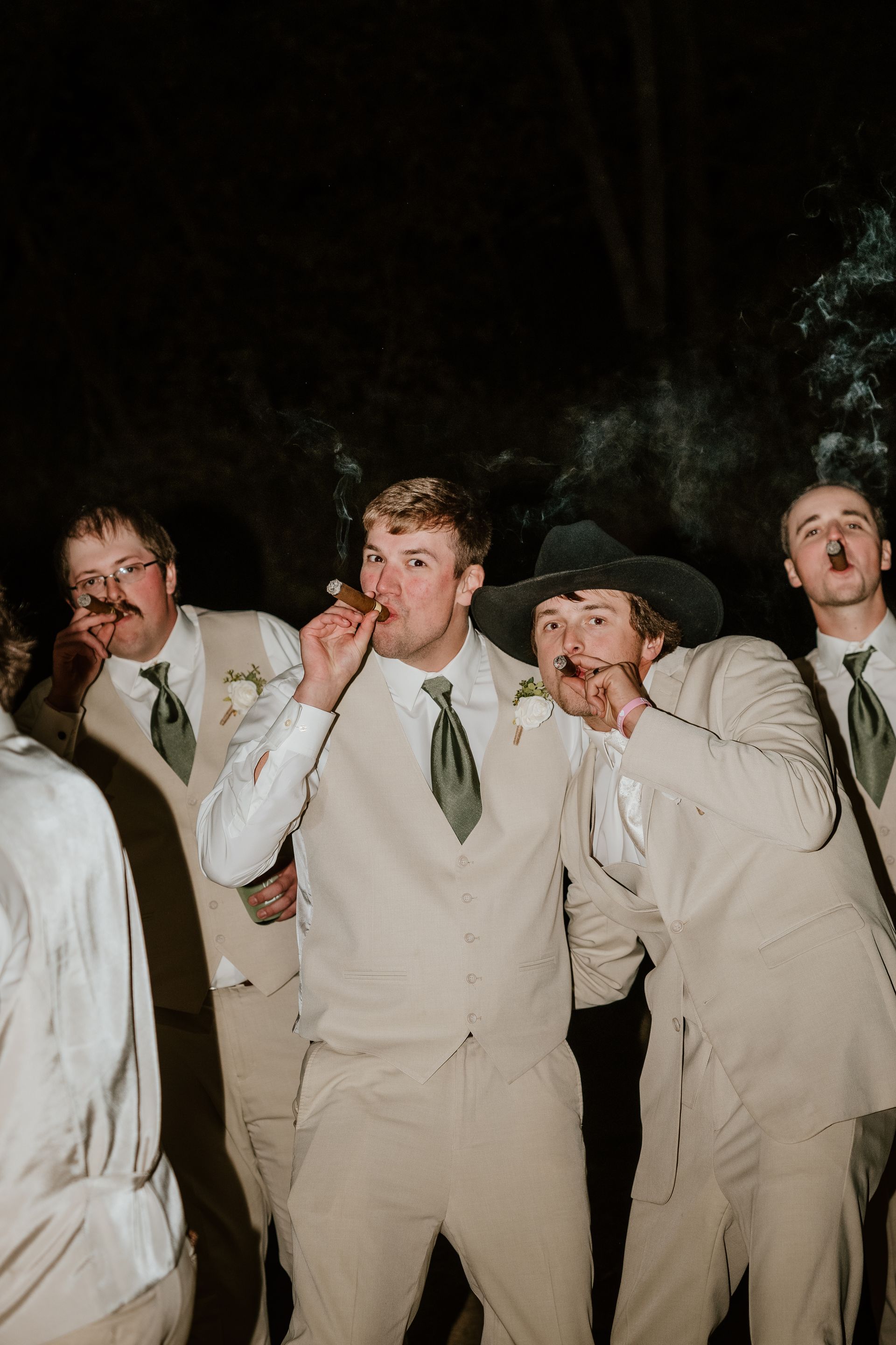 four men are smoking cigars together and have their arms around eachother