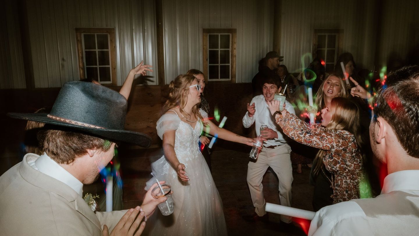 A bride and groom are dancing with glow sticks at their wedding reception.