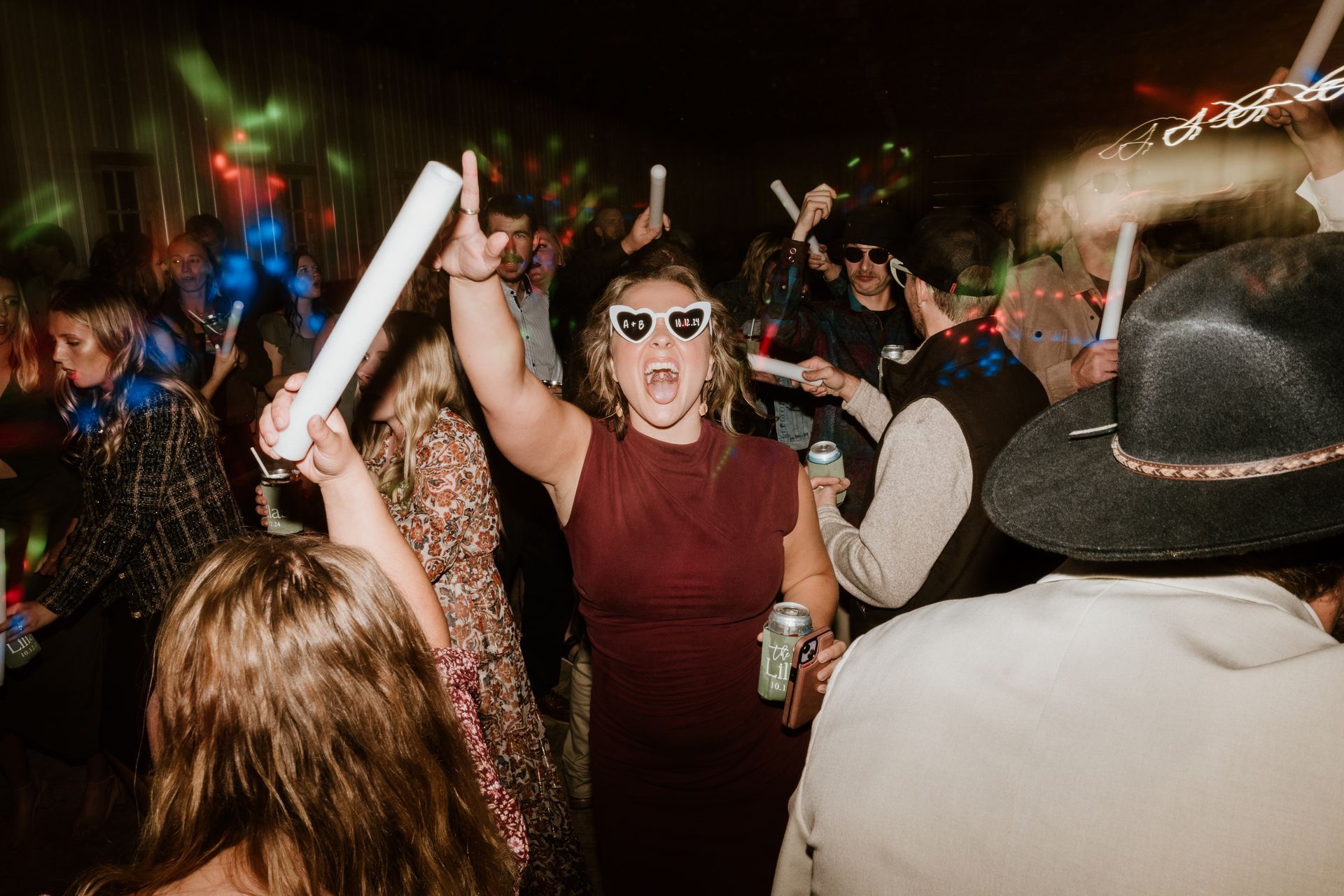 A woman wearing sunglasses is dancing in a crowd of people at a party.