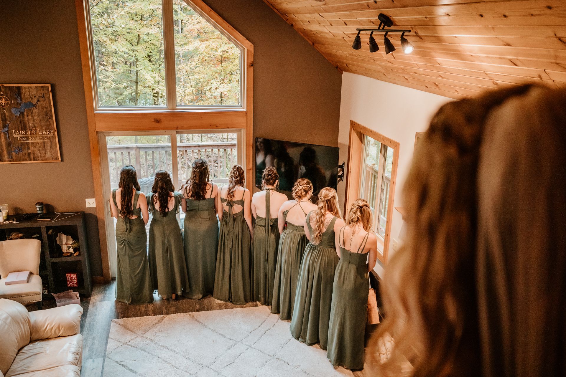 A bride and her bridesmaids are standing in a living room.
