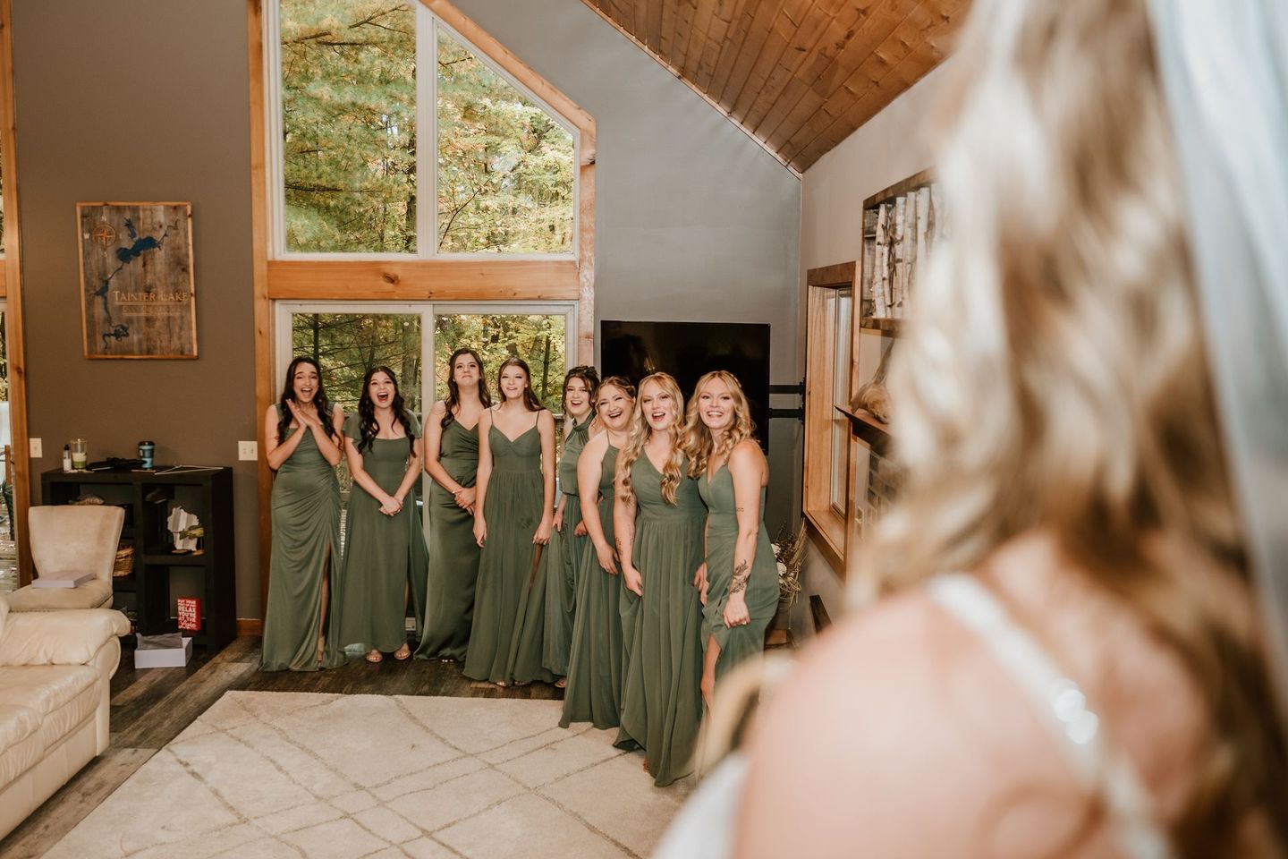 A bride and her bridesmaids are standing in a living room.