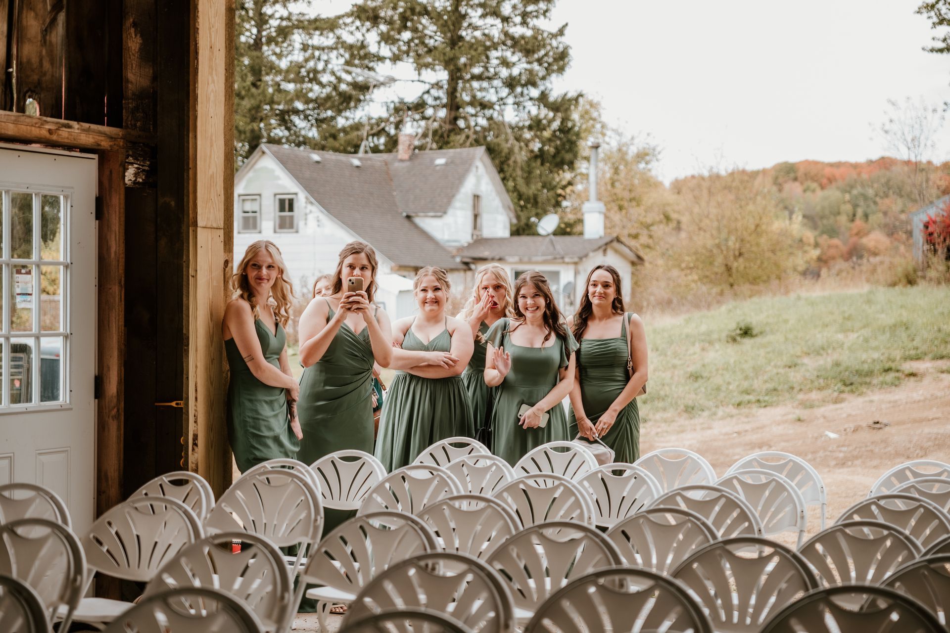 A group of bridesmaids standing in front of a row of chairs.
