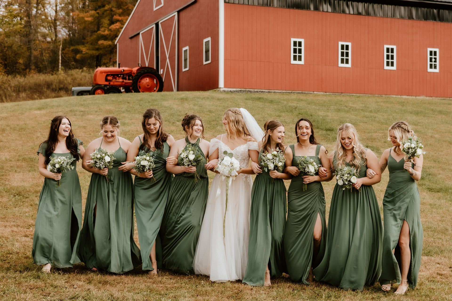 A bride and her bridesmaids are posing for a picture in front of a barn.