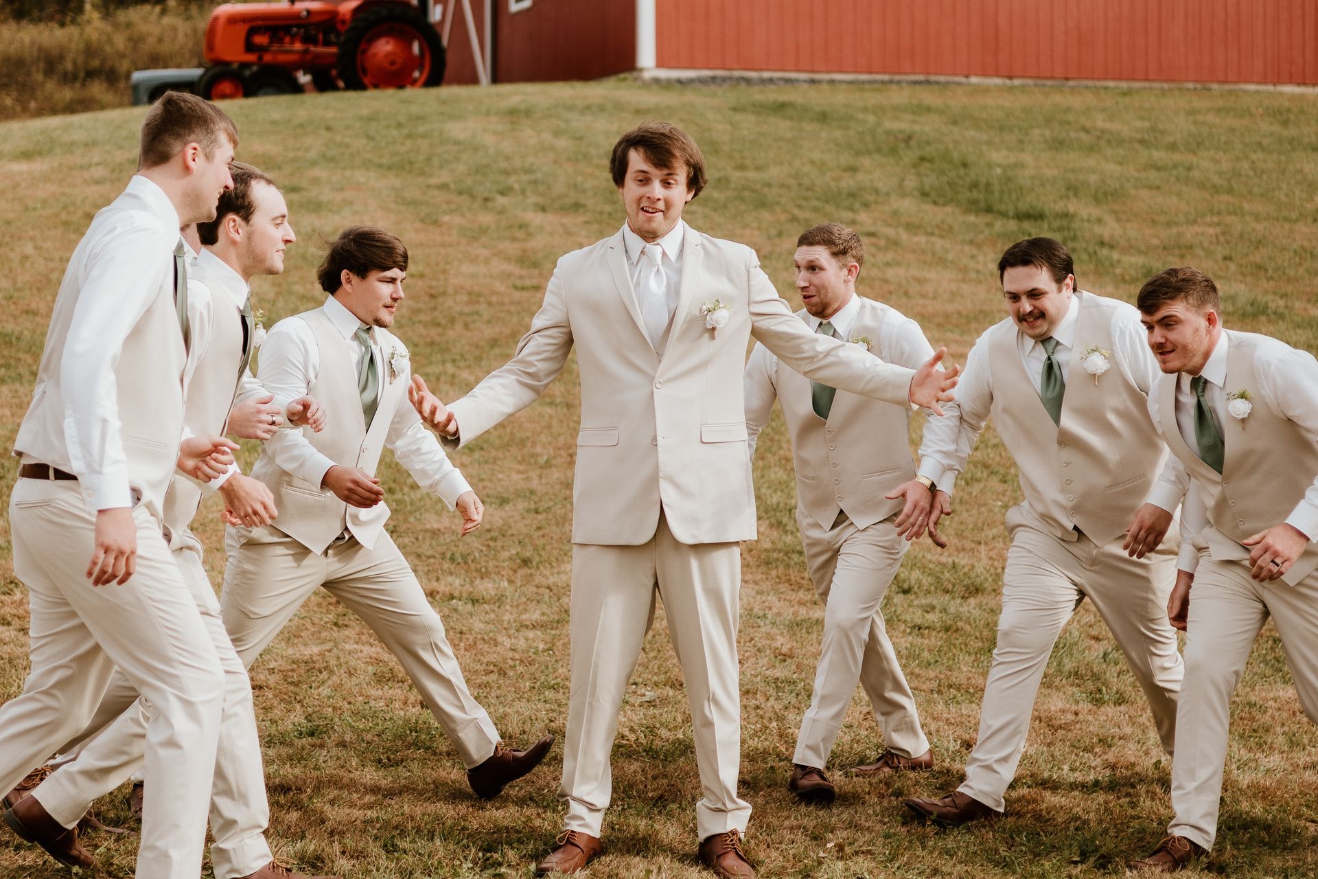 A groom and his groomsmen are posing for a picture in a field.