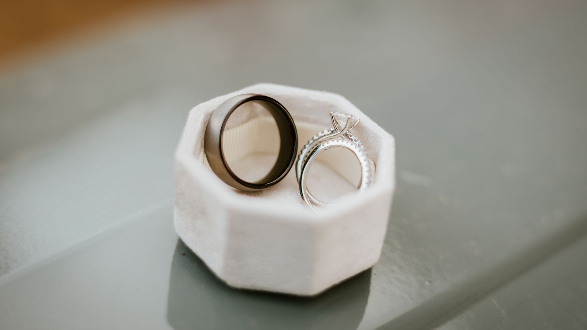 Two wedding rings are sitting in a white box on a table.