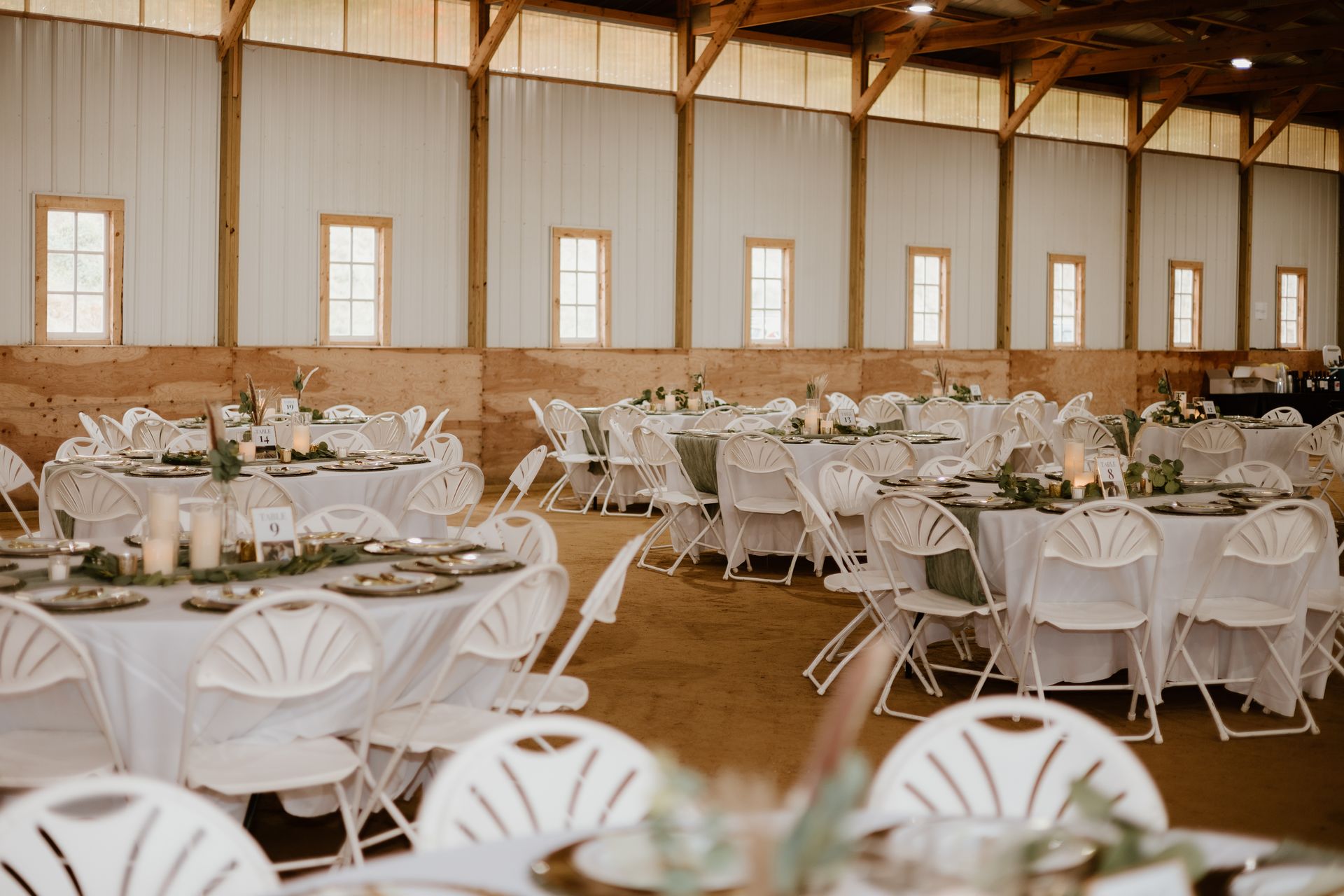 A large room with tables and chairs set up for a wedding reception.