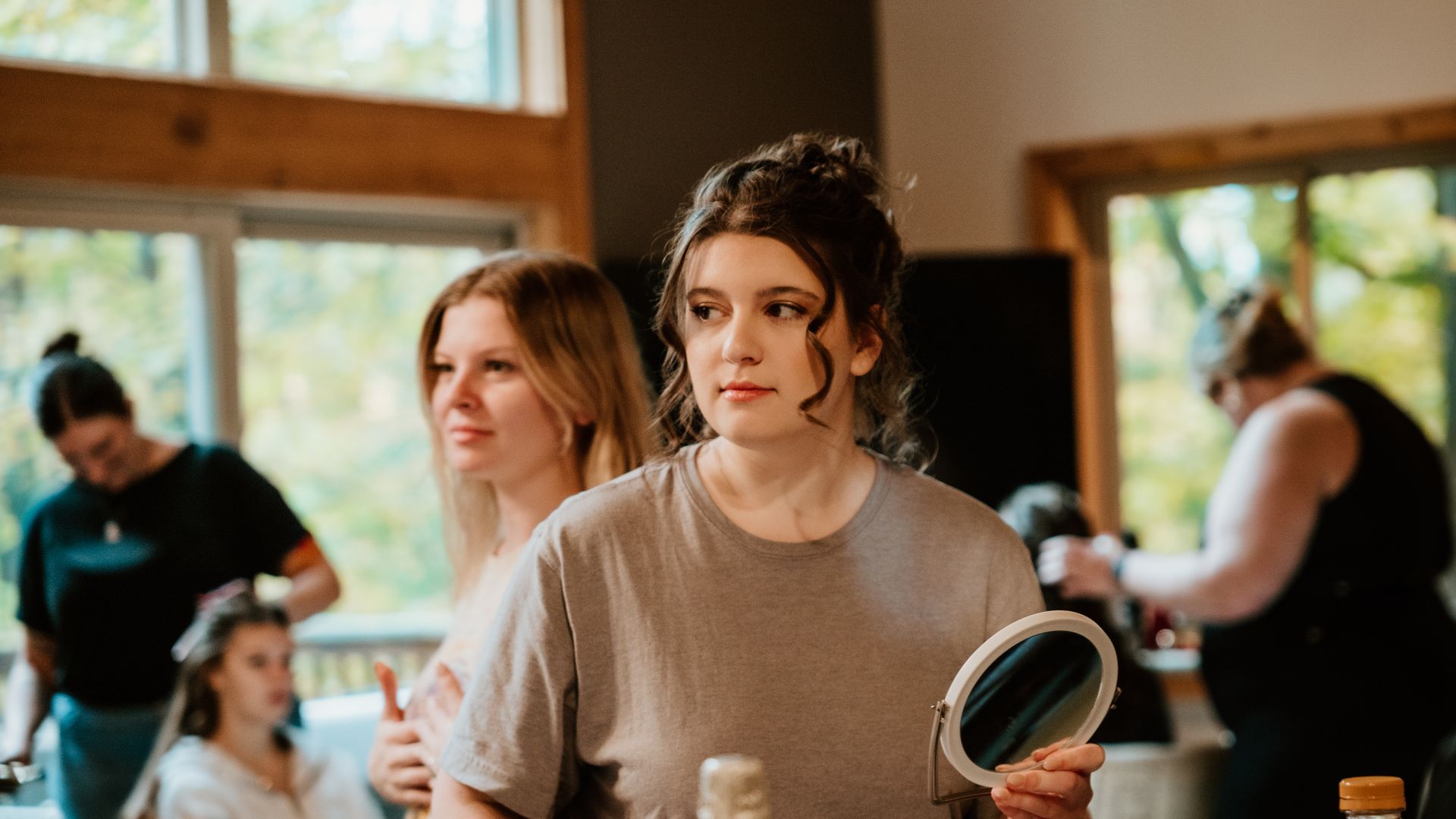 A woman is looking at herself in a mirror while getting ready for a wedding.