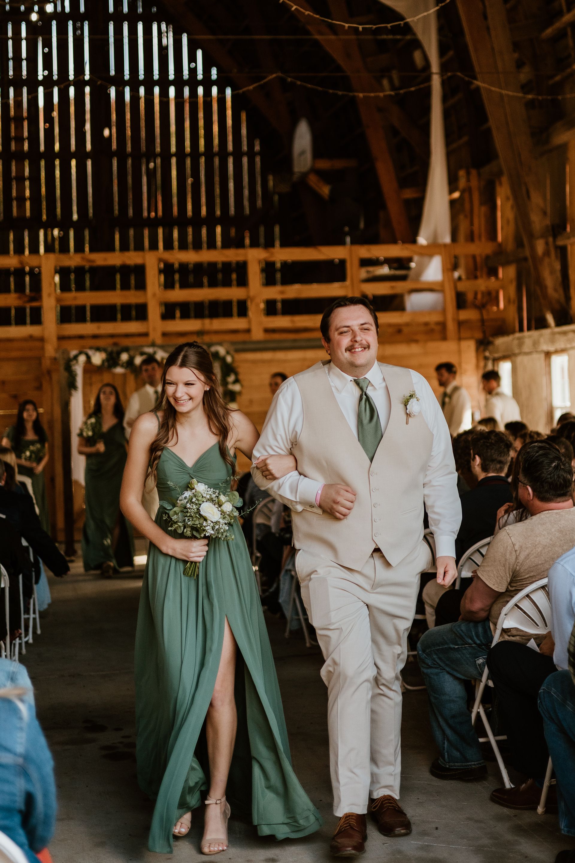 A bride and groom are walking down the aisle at their wedding in a barn.