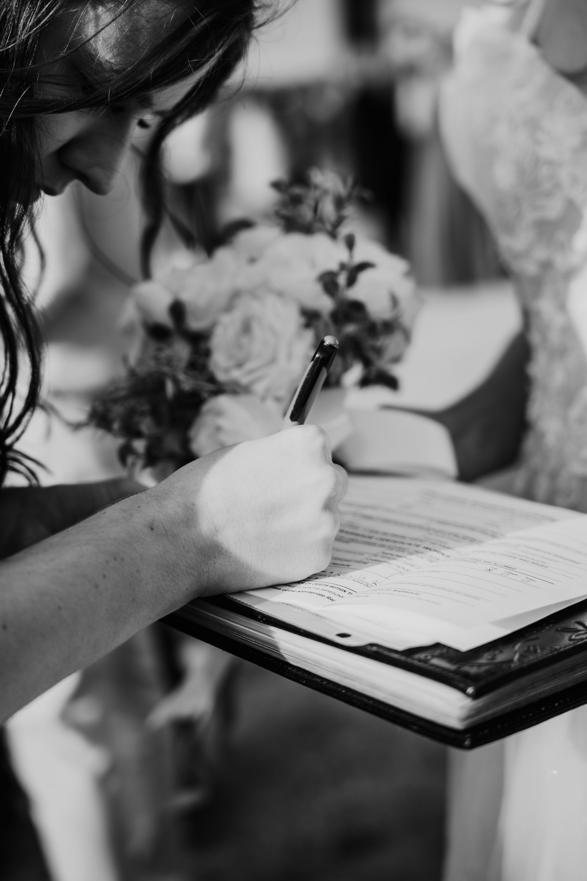 A woman is writing on a piece of paper with a pen.