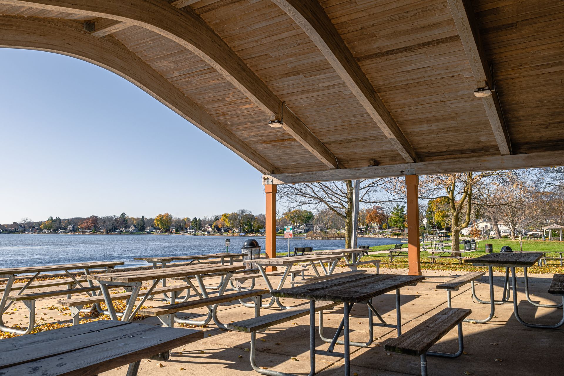 A picnic area with tables and benches overlooking a lake.