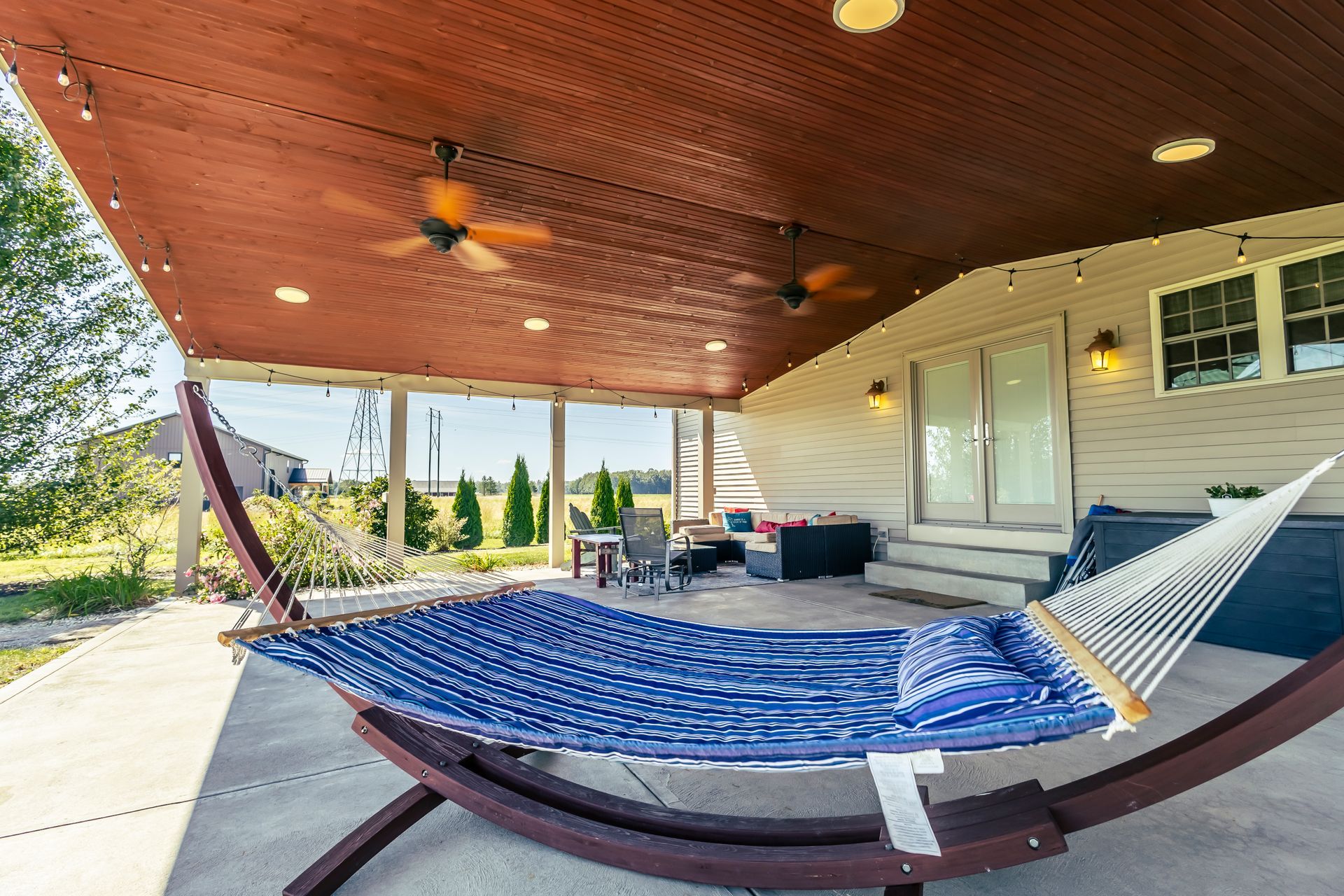 A blue hammock is sitting on a porch under a ceiling fan.