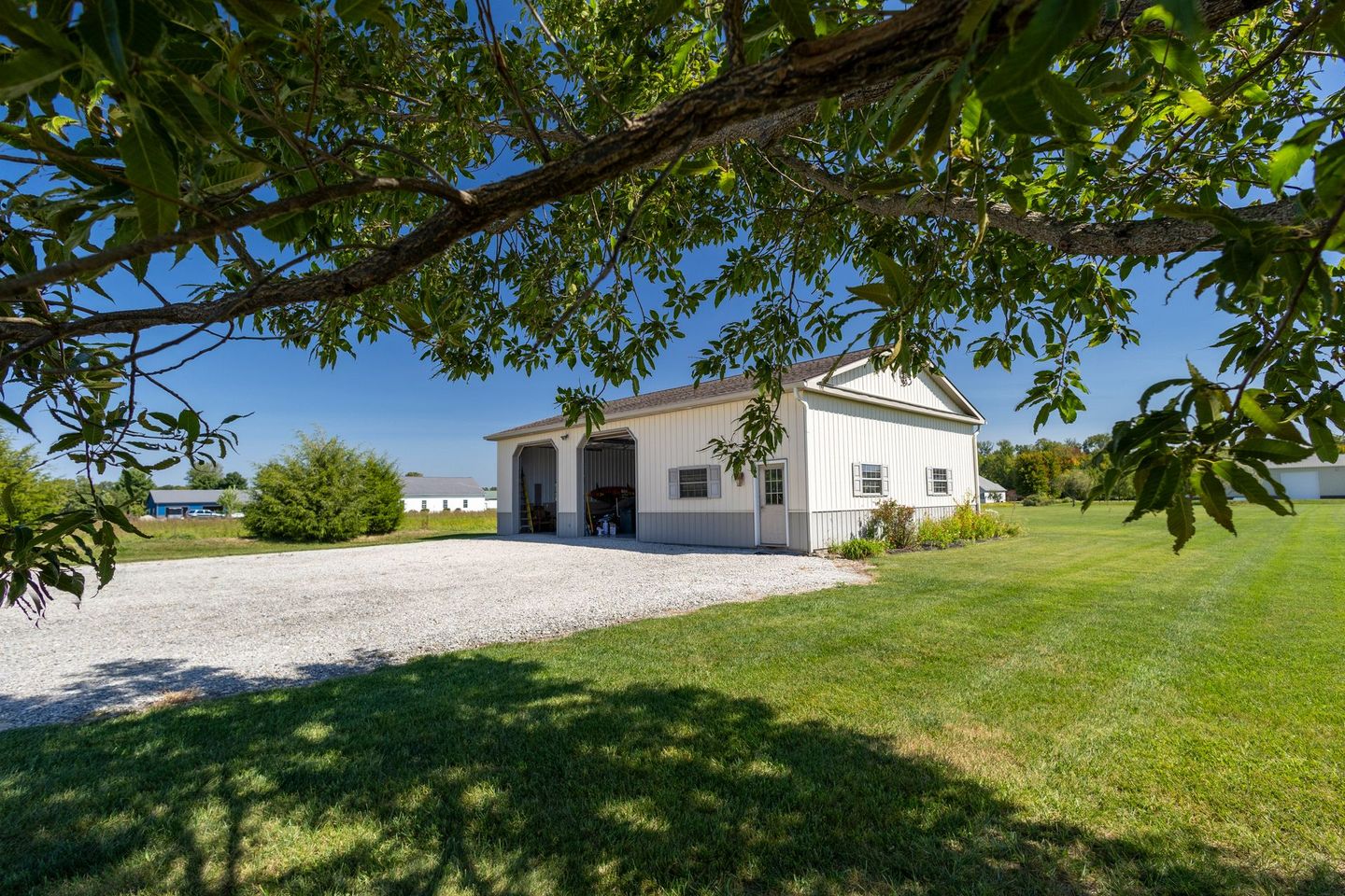 A white barn is sitting in the middle of a grassy field.