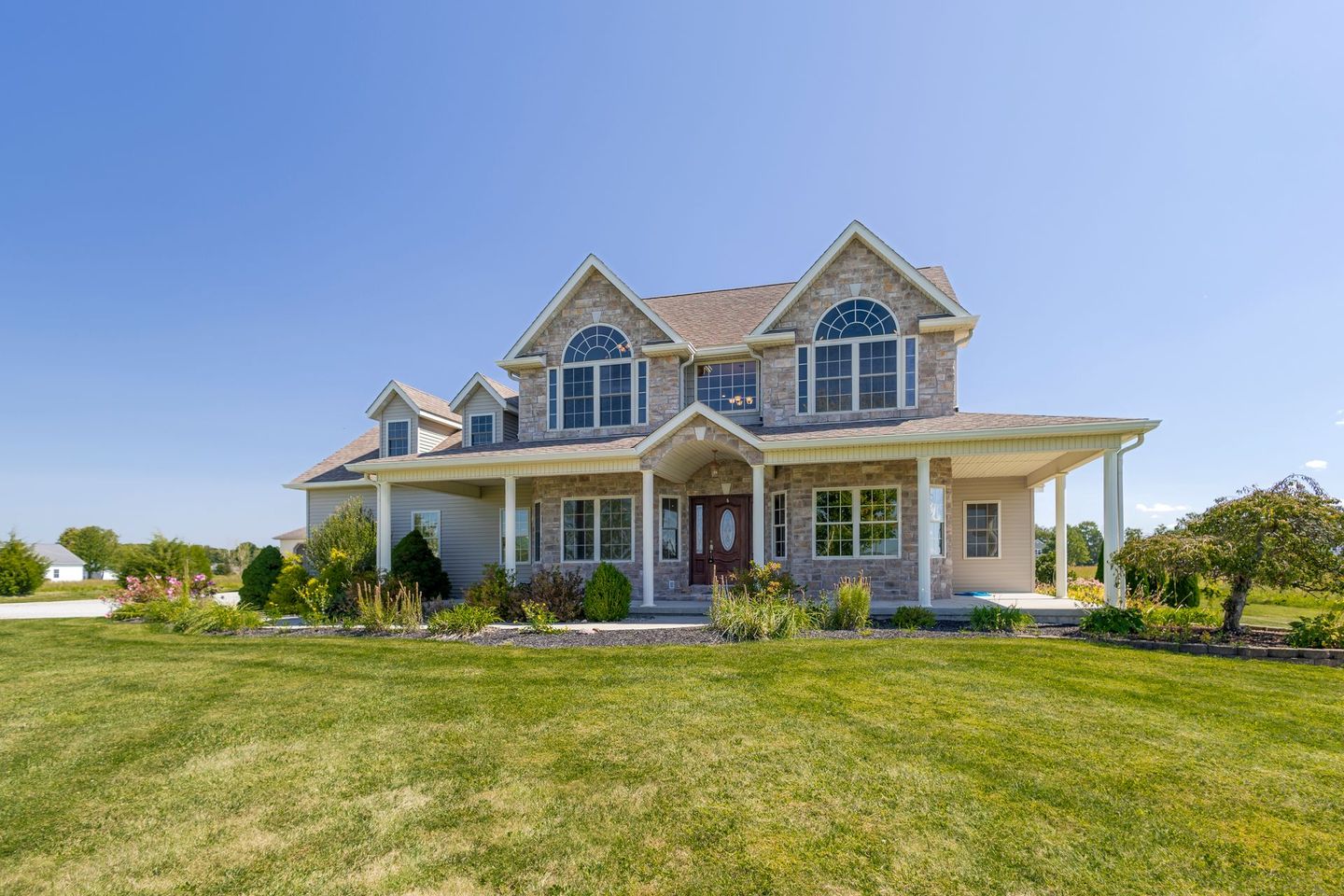 A large house is sitting on top of a lush green field.