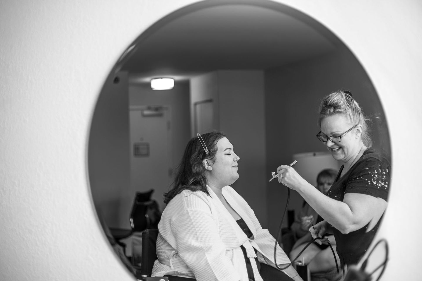 A woman is getting her hair done in front of a mirror.