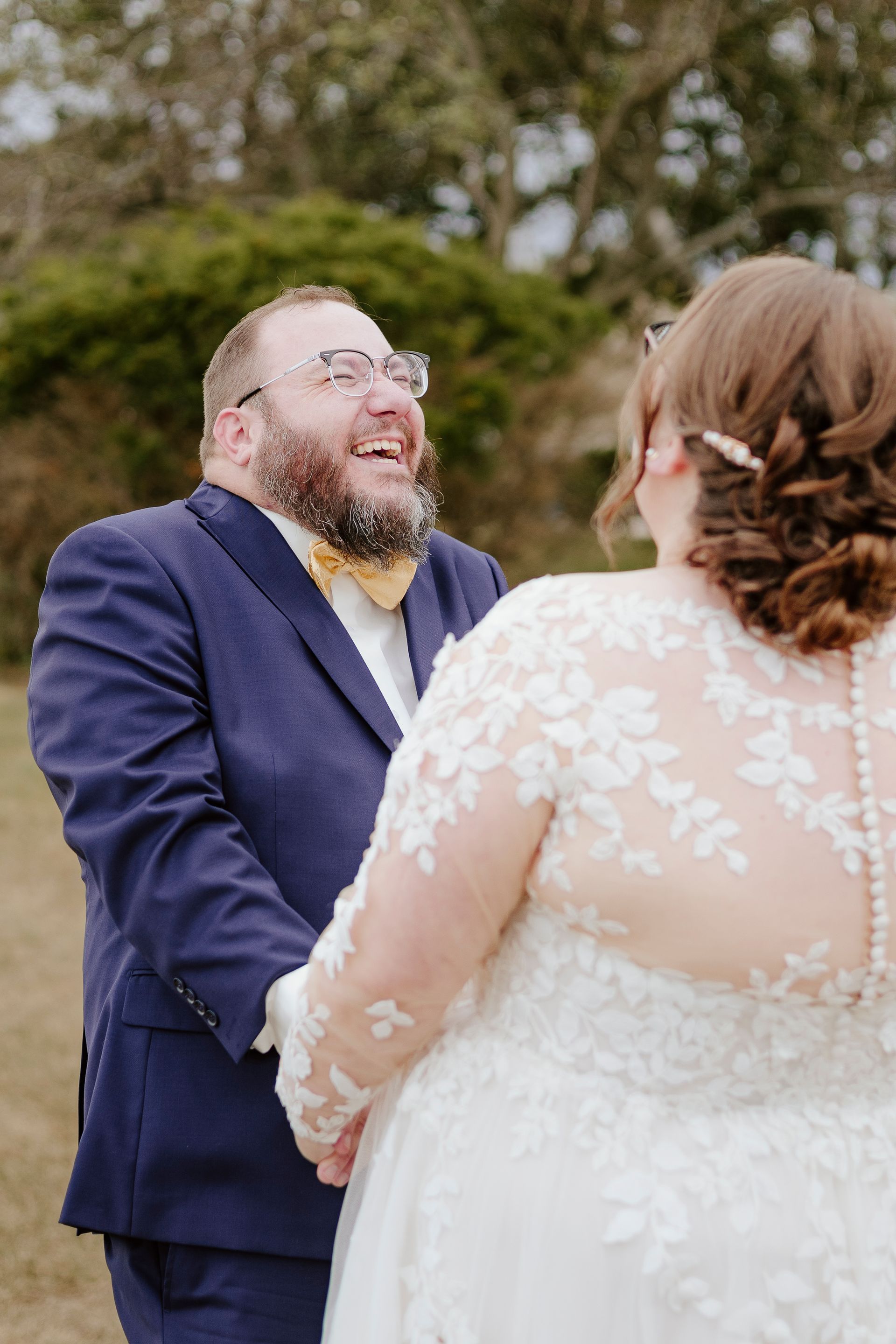 A bride and groom are holding hands during their first look at their wedding.