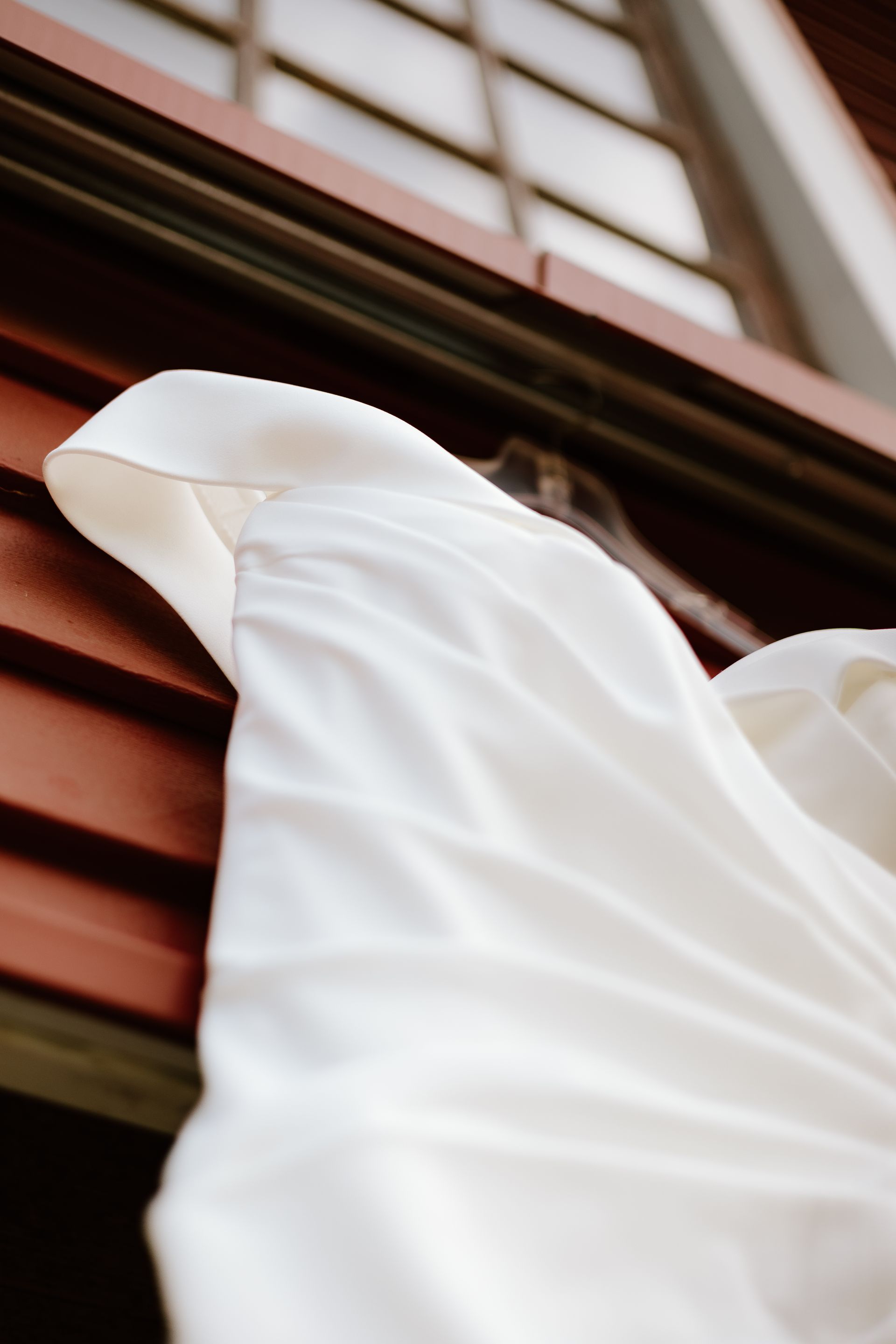 A white dress is hanging on a window sill.