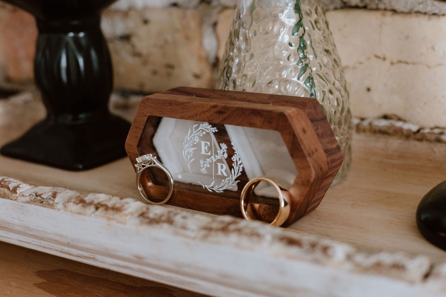 Two wedding rings are sitting in a wooden box on a table.