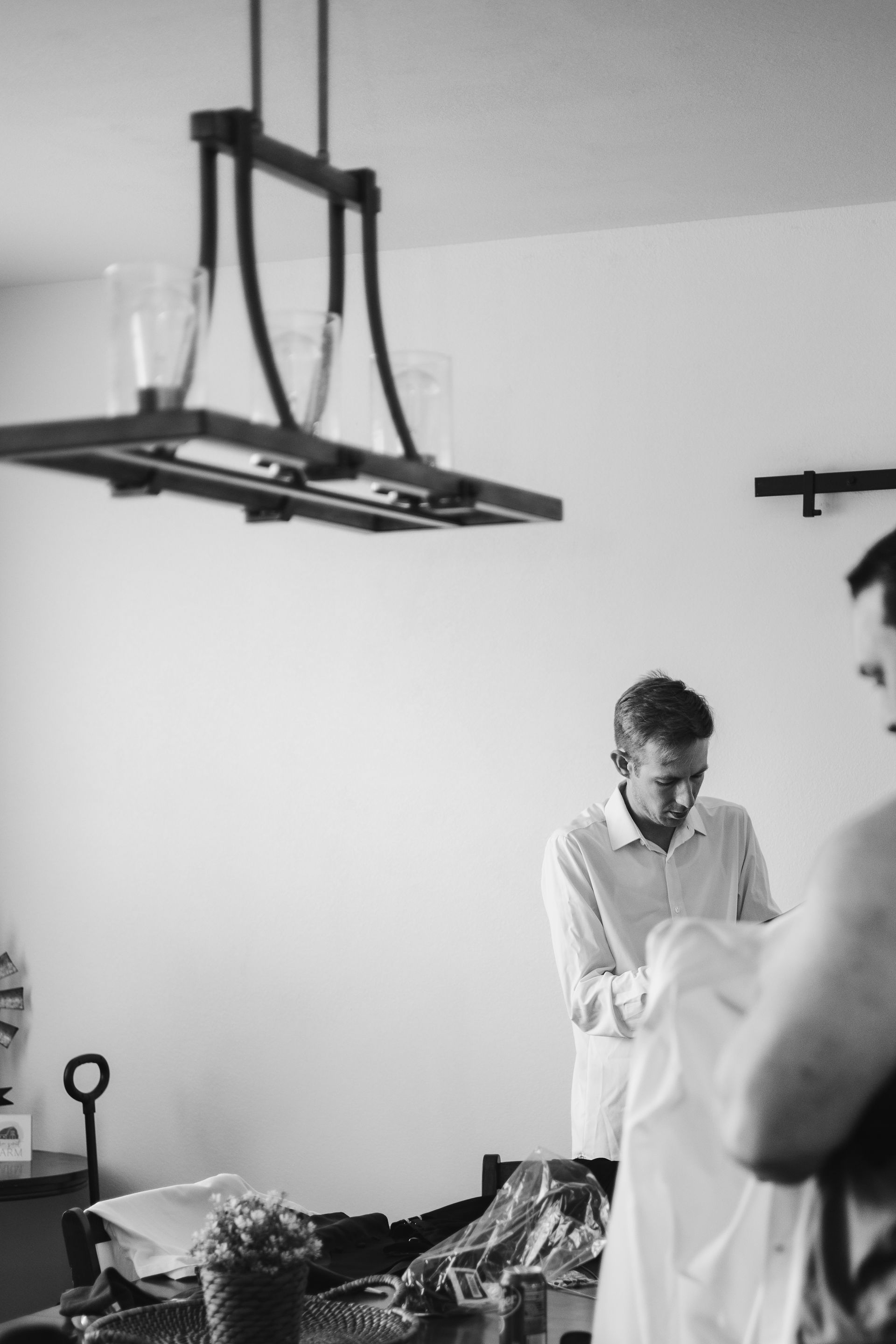 A man is getting ready for his wedding in a black and white photo.