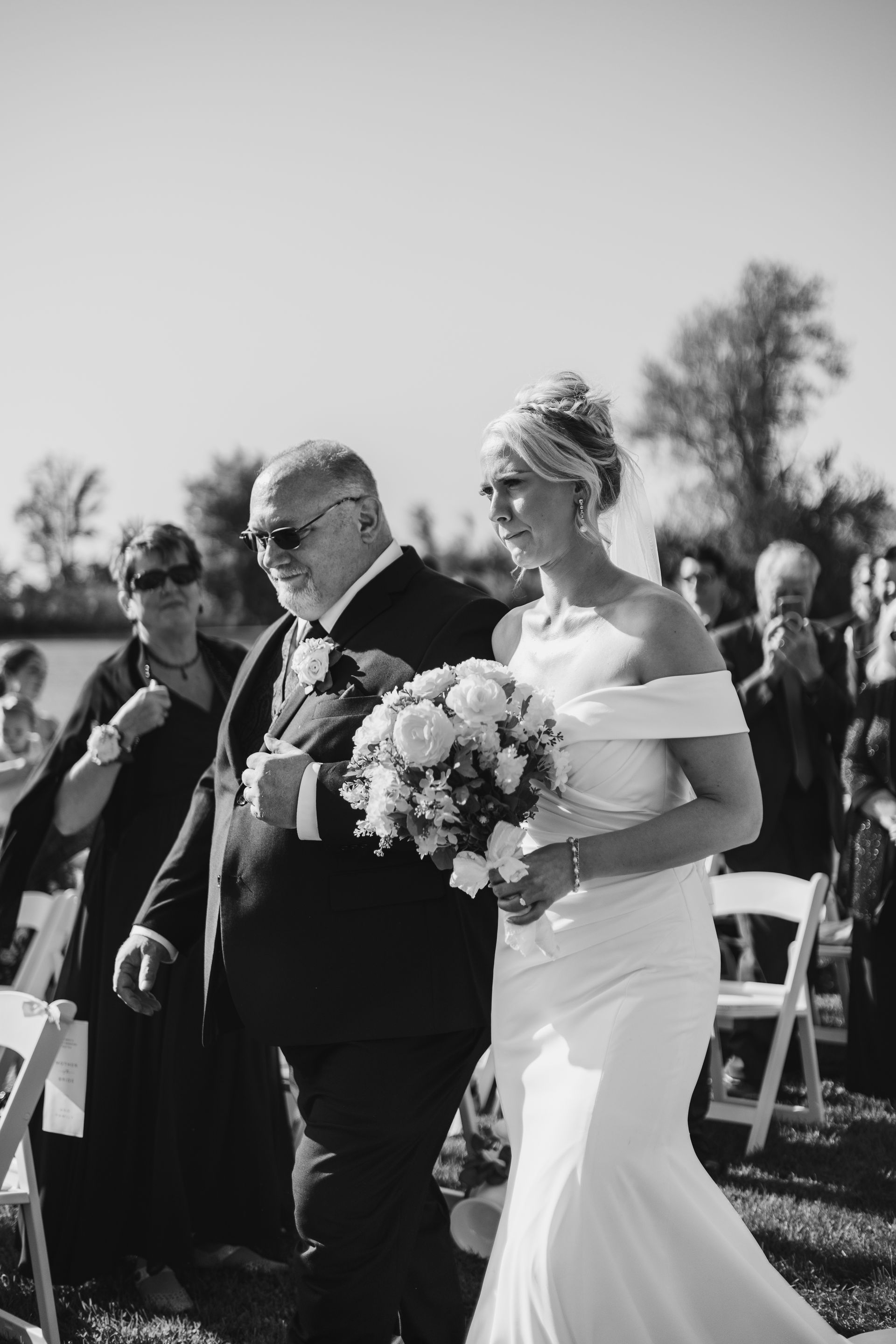 A black and white photo of a bride walking down the aisle with her father.