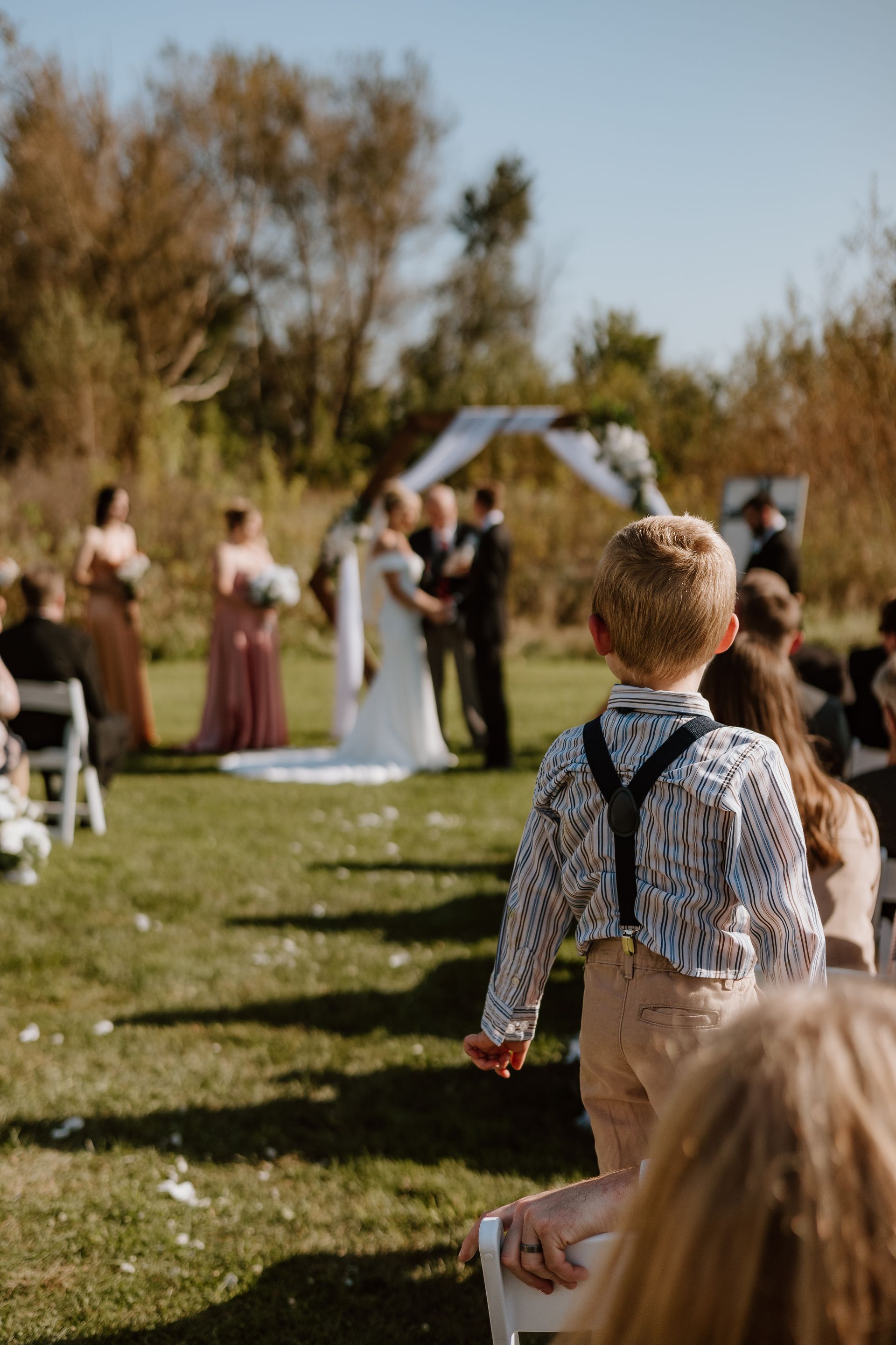 A little boy is holding a flower at a wedding ceremony.