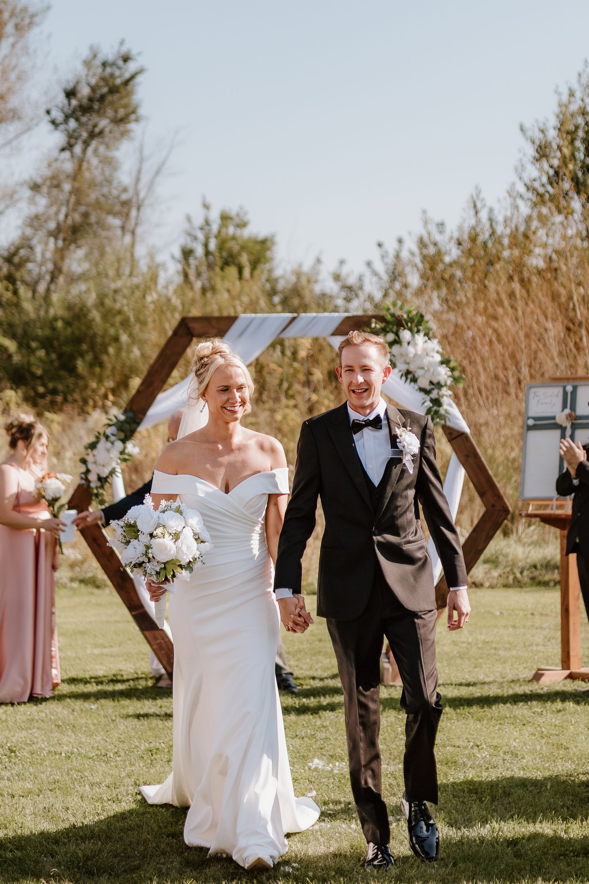 A bride and groom are walking down the aisle at their wedding holding hands.