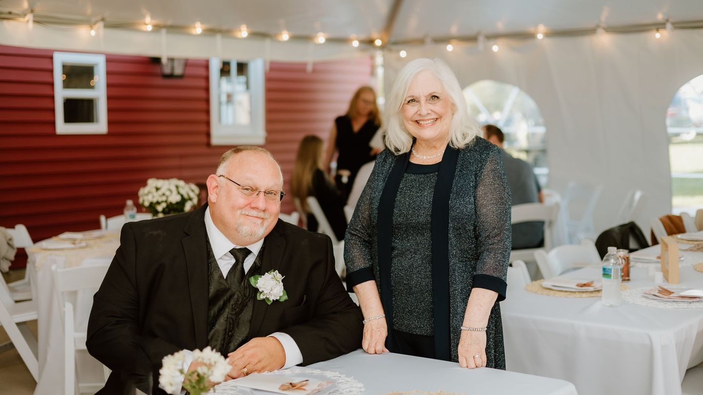 A man and a woman are standing next to each other at a table at a wedding reception.