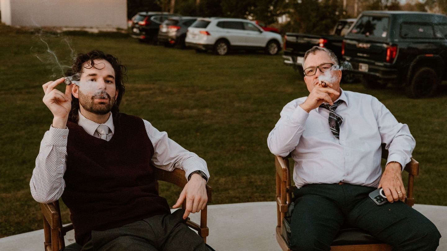 two men are smoking cigars sitting down