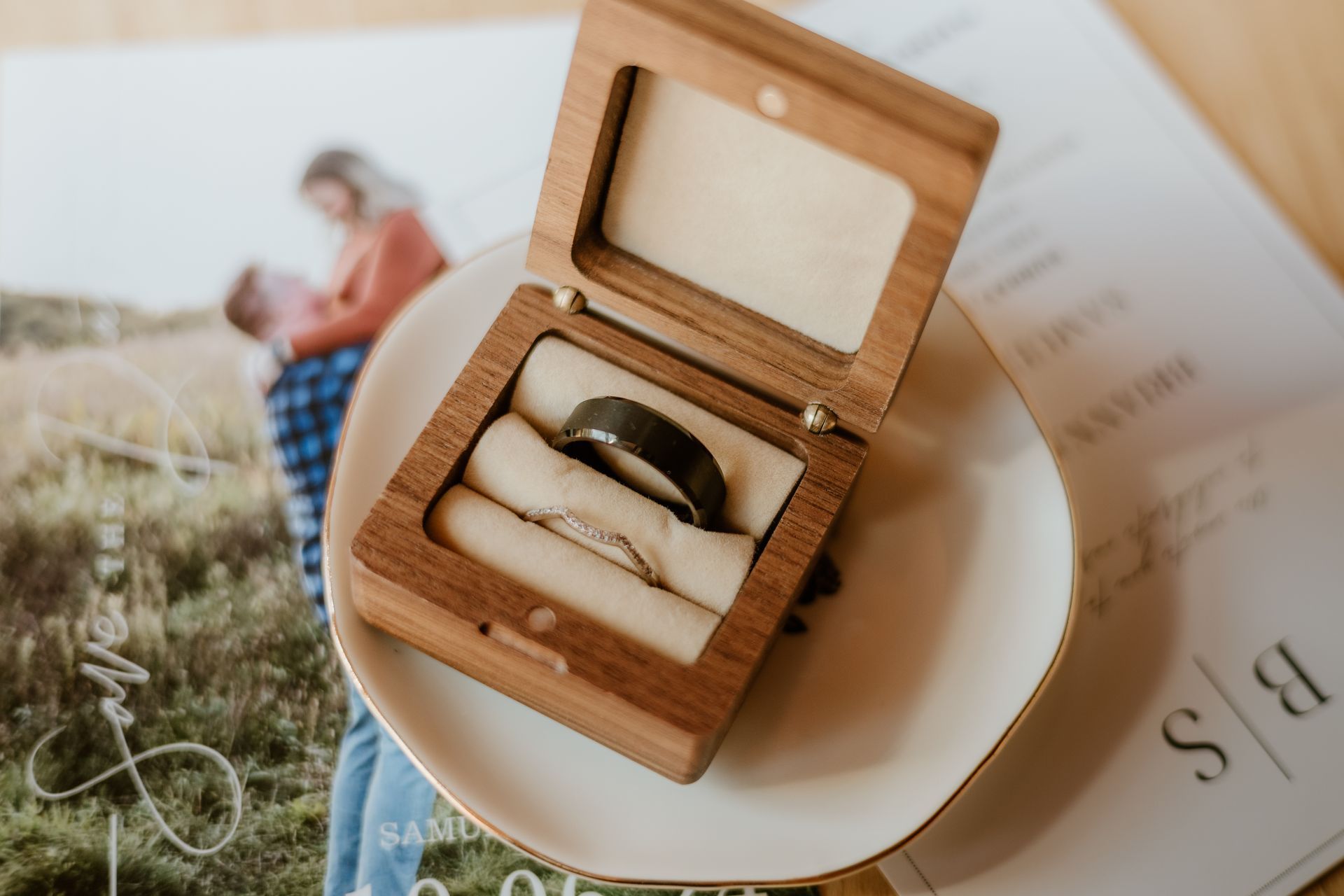 A pair of wedding rings in a wooden box on a plate.