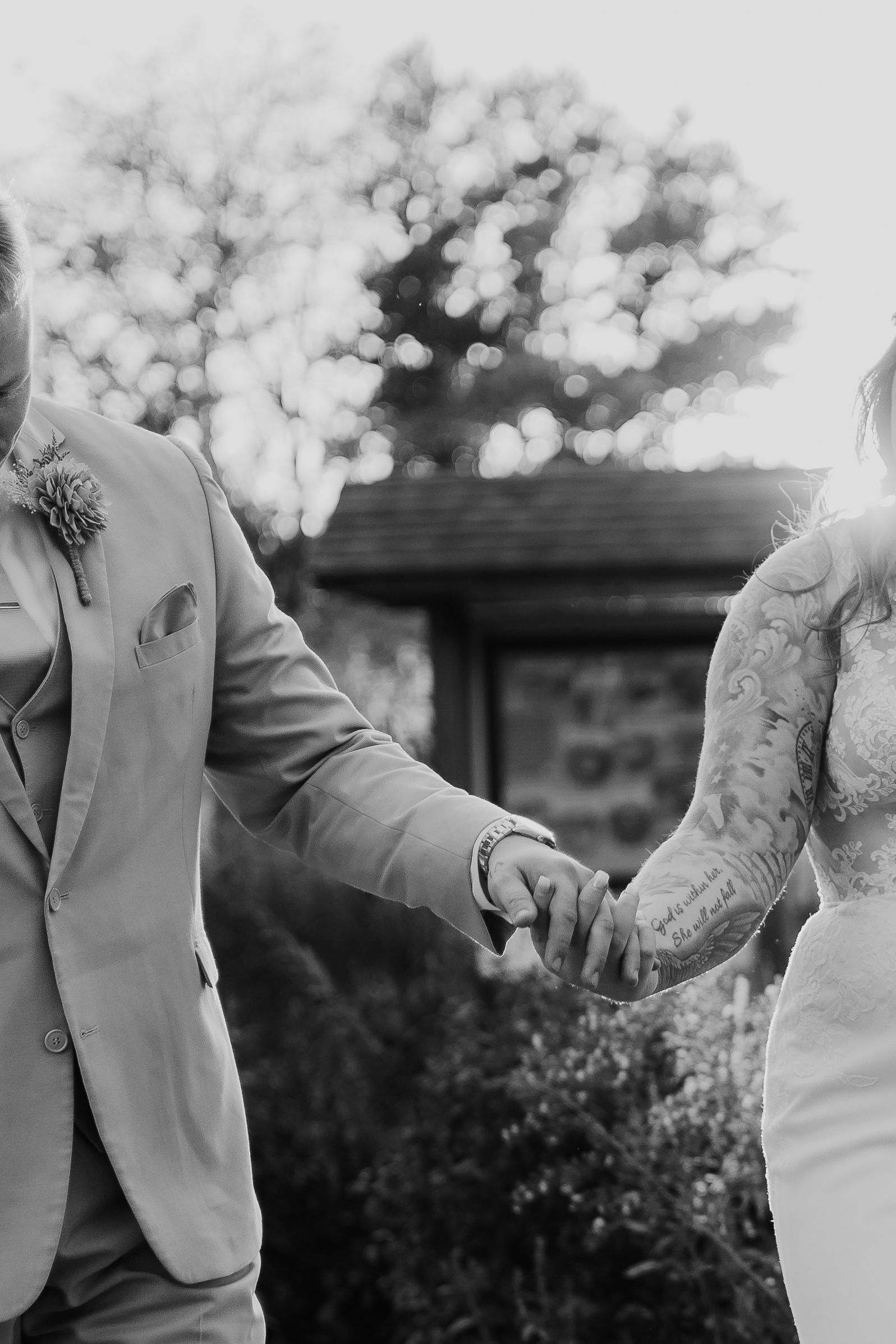 A bride and groom are holding hands in a black and white photo.