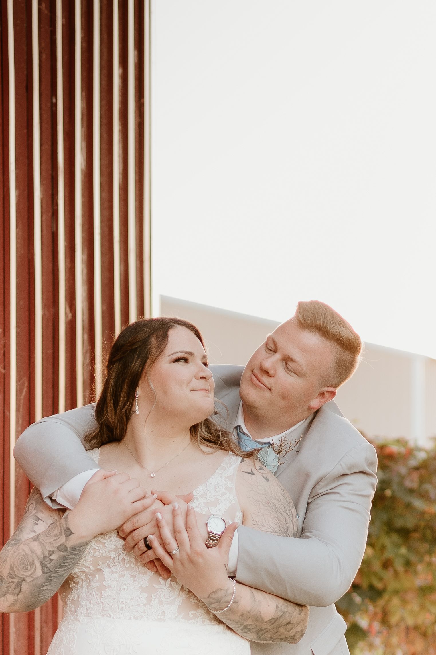 A bride and groom are posing for a picture in front of a red barn.